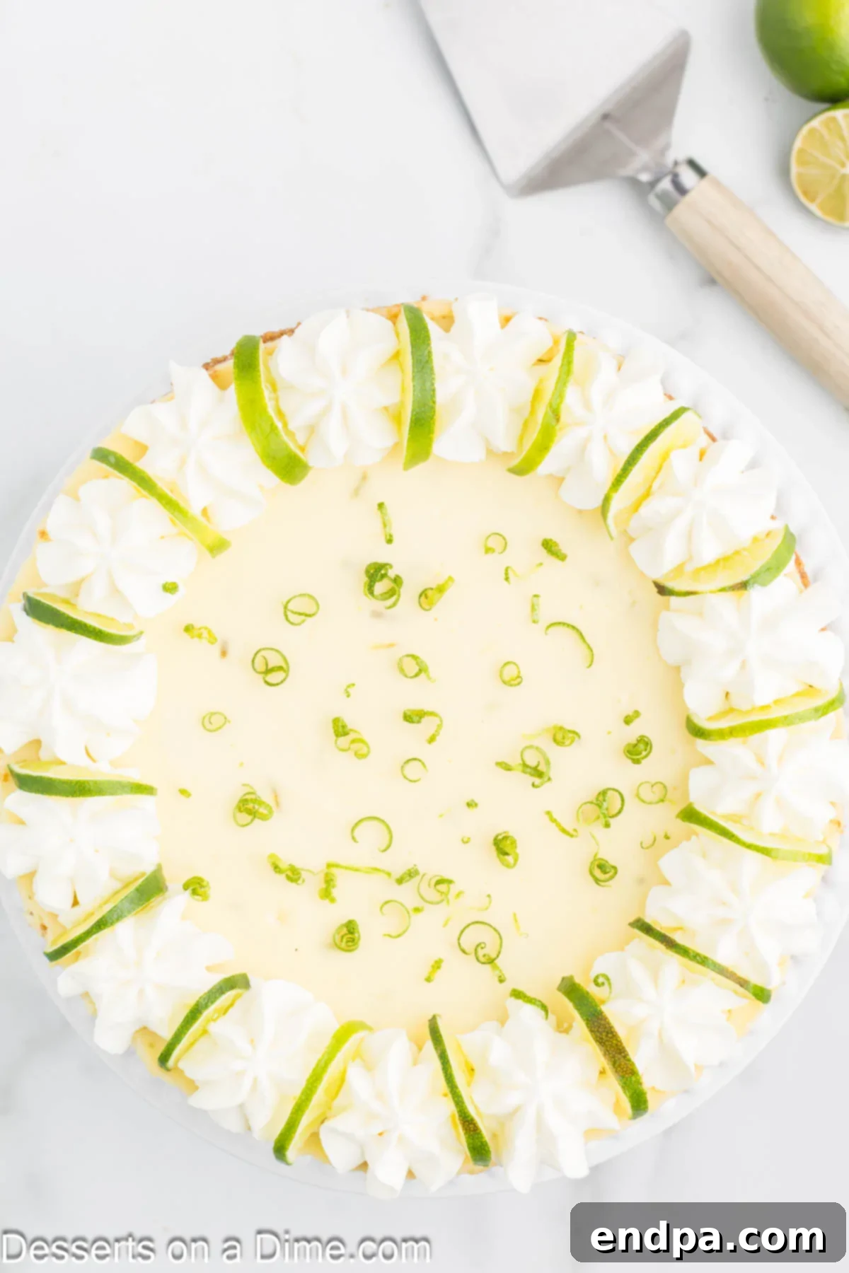 Beautiful Key Lime Cheesecake decorated with piped whipped cream and fresh lime slices, ready to be served.