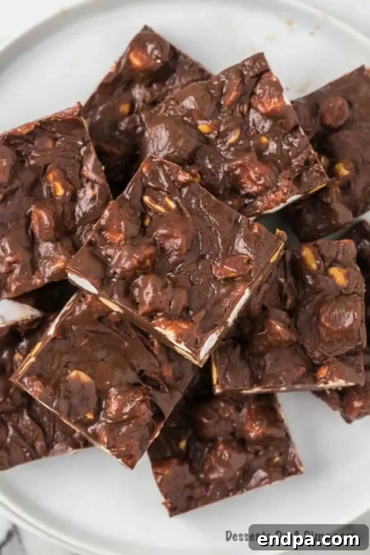 Platter of Rocky Road Fudge cut into slices. Irresistibly rich chocolate fudge, studded with fluffy marshmallows and crunchy salted peanuts, perfectly portioned for sharing or individual indulgence.