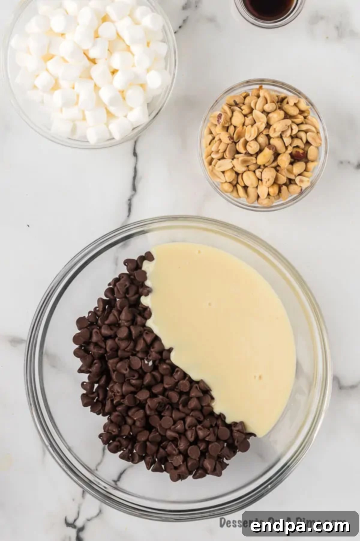 Mixing bowl with chocolate and sweetened condensed milk. A glass bowl filled with semi-sweet chocolate chips and creamy sweetened condensed milk, ready for melting.