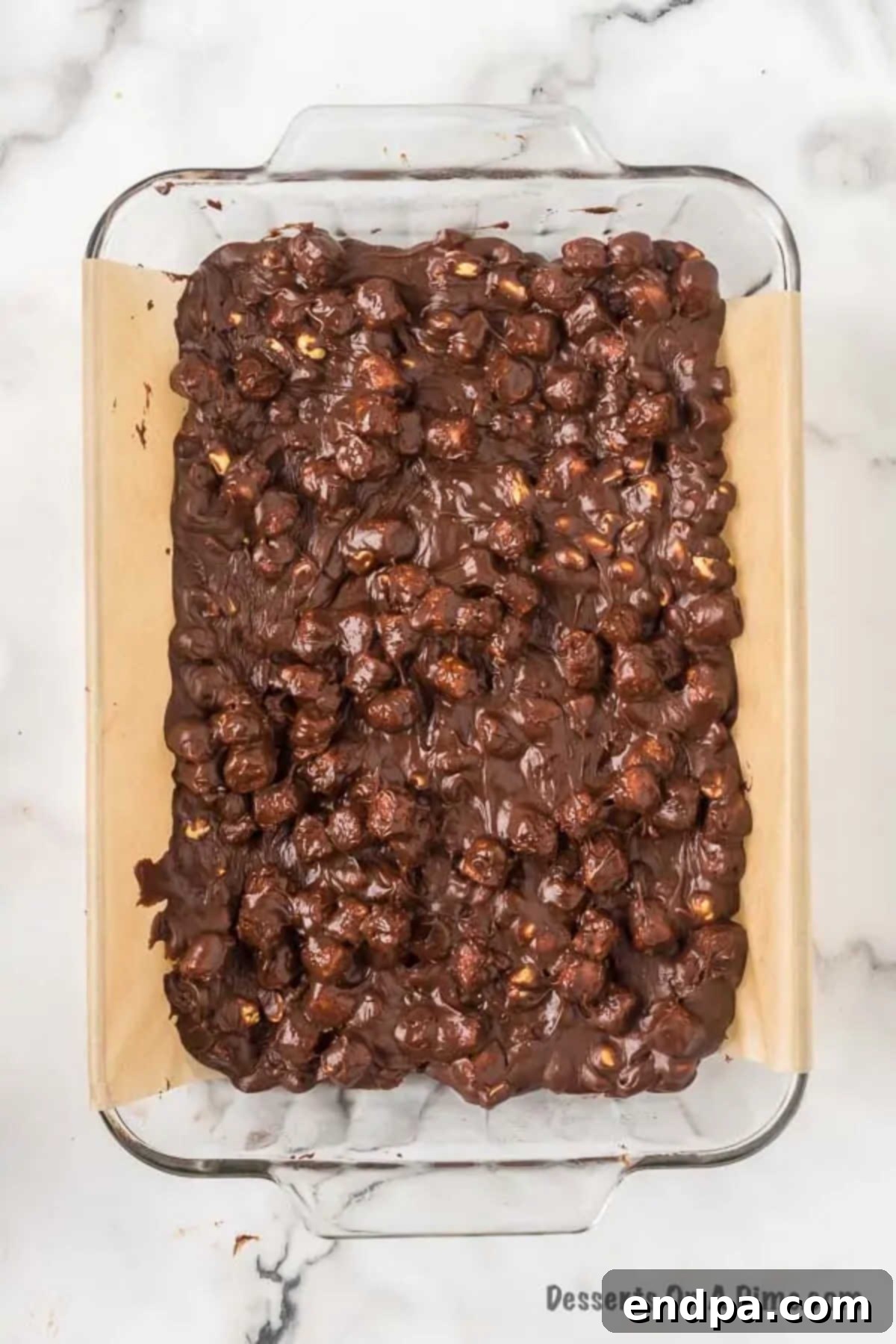 Fudge mixture spread in pan. The Rocky Road fudge mixture smoothly spread into the prepared 9x13 inch baking pan, ready for chilling.