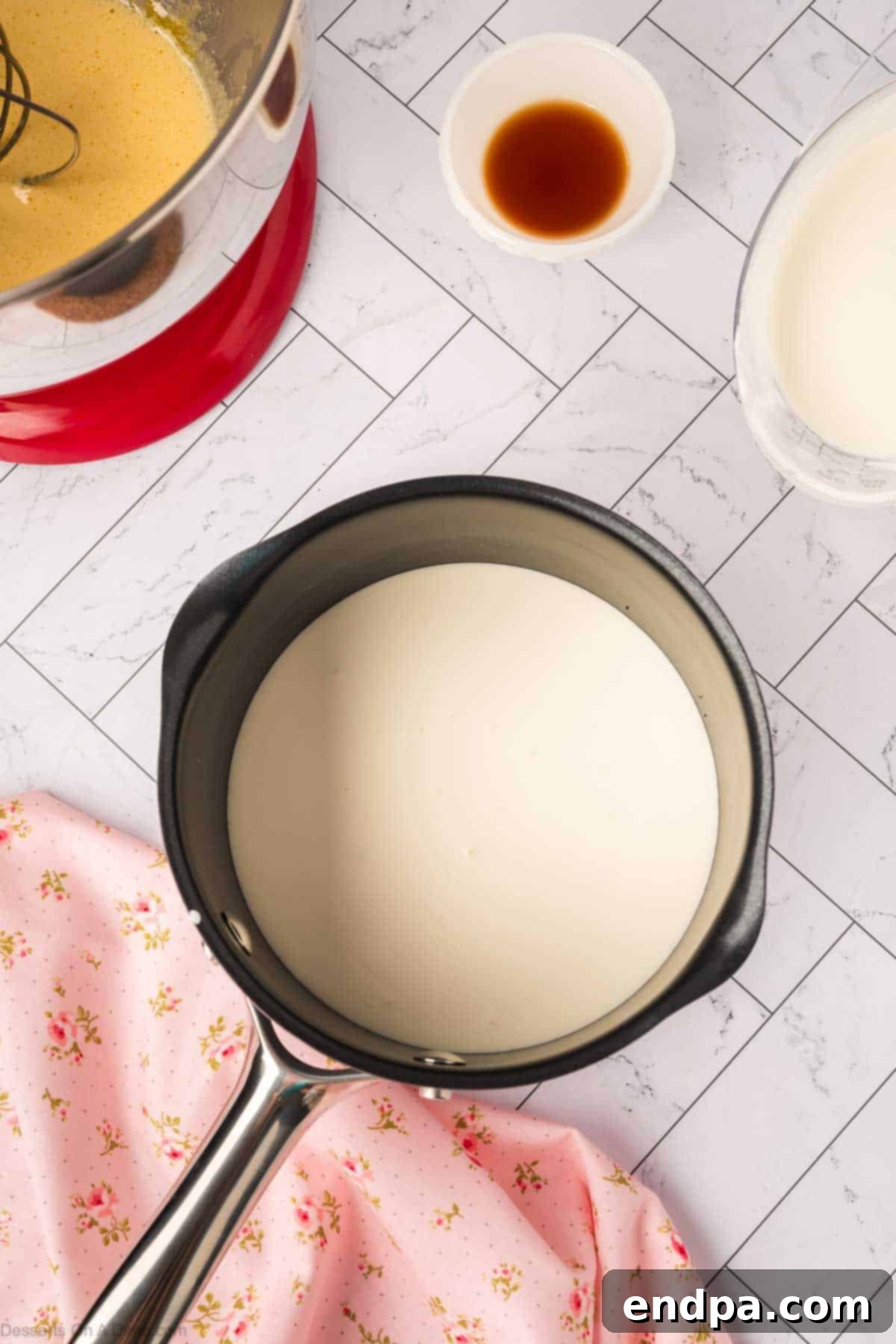 Heavy cream being heated in a small saucepan.