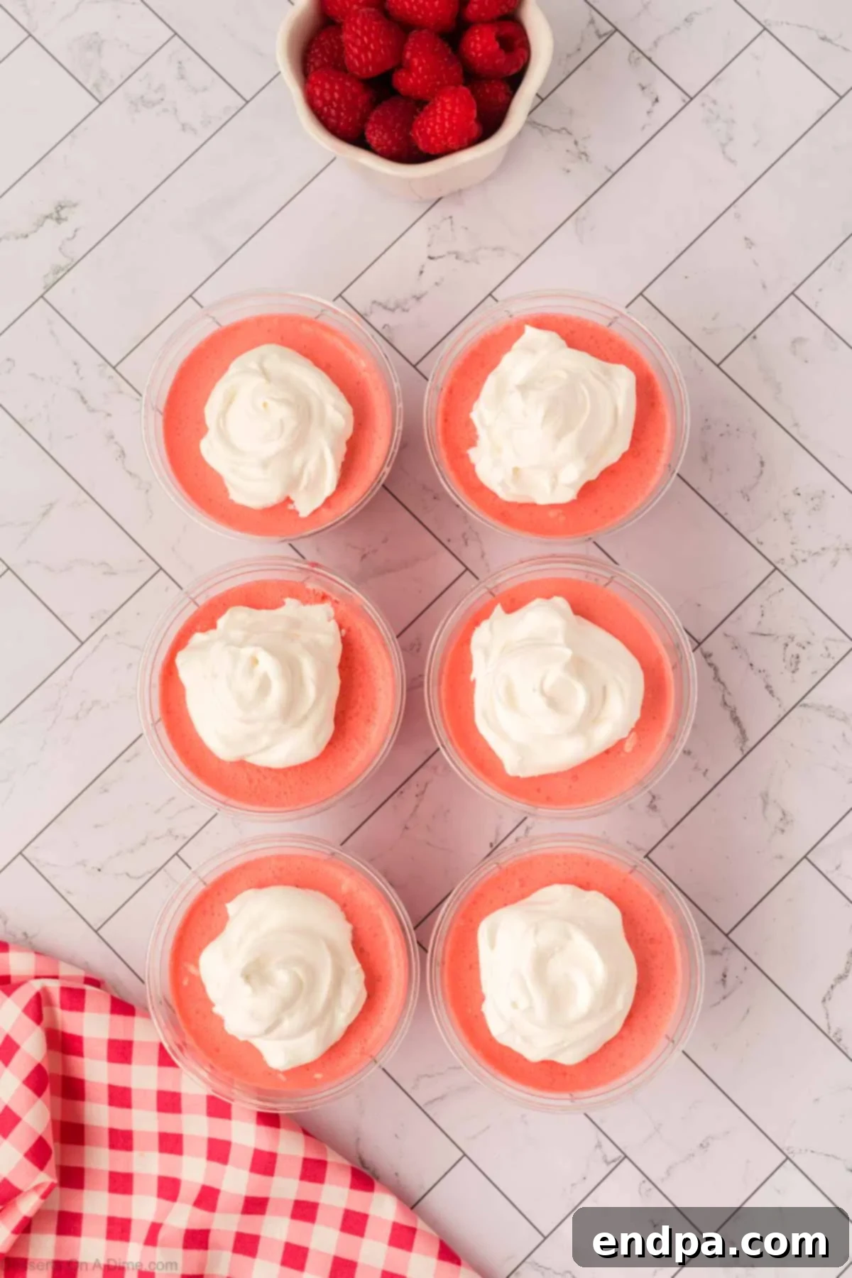 Layered Gelatin Delight 11 Individual Jello parfaits topped with generous dollops of whipped cream, ready for final garnish.