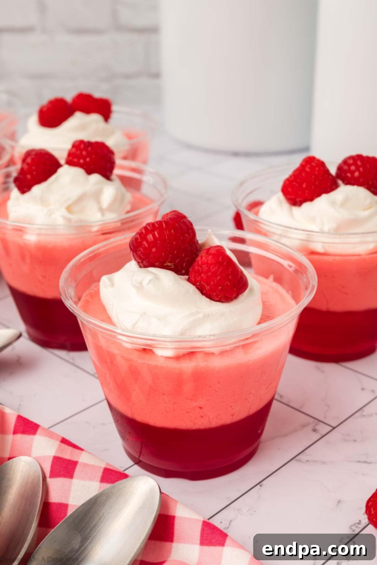 Layered Gelatin Delight 12 Close-up of a beautifully layered Jello Parfait with whipped cream and fresh raspberries, showcasing its vibrant layers.