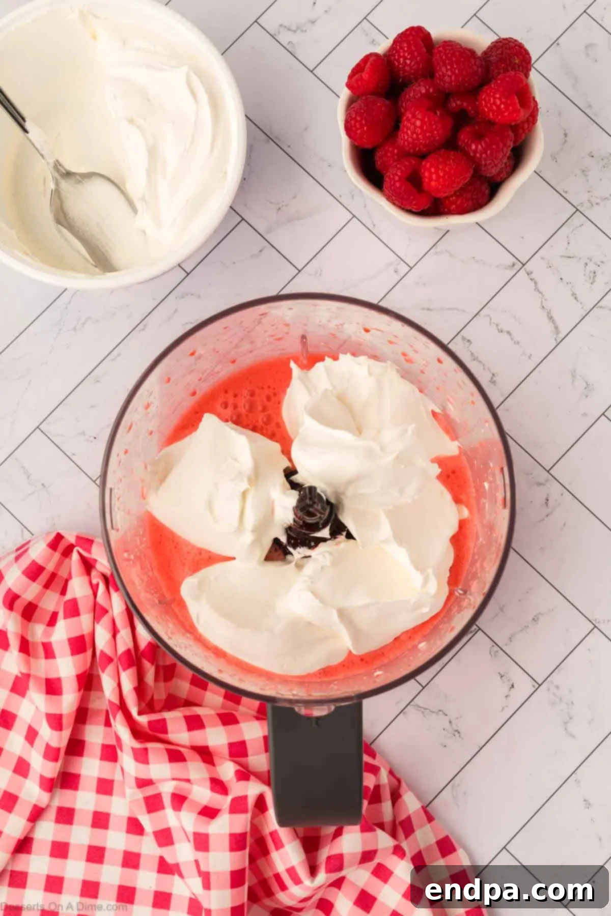 Layered Gelatin Delight 8 Whipped topping being added to the Jello and cream cheese mixture in the food processor.