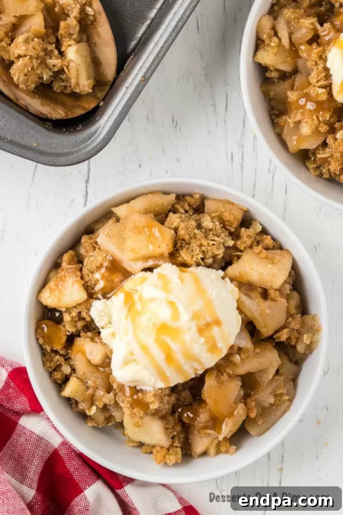 Buttery Oat Apple Crisp 3 Warm apple crisp in a bowl with a scoop of vanilla ice cream and a drizzle of caramel sauce.