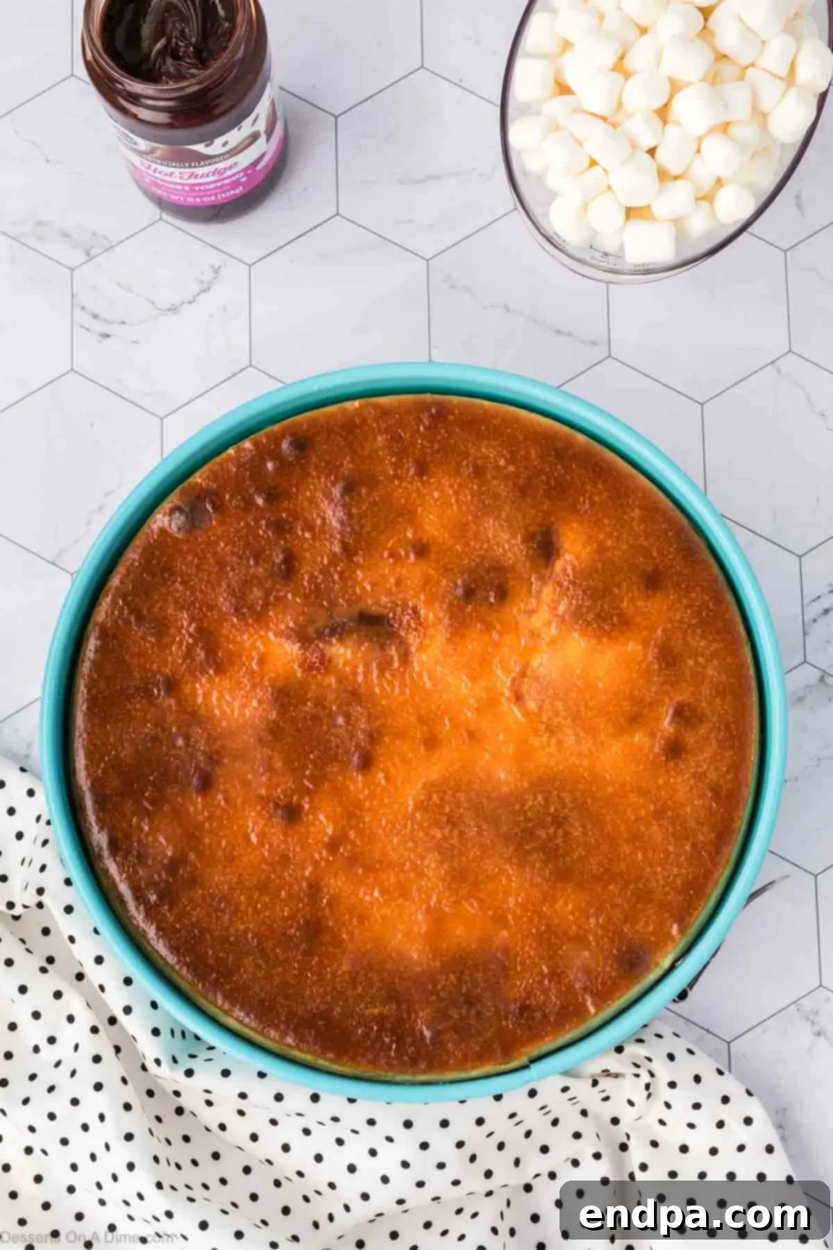 A baked S'mores Cheesecake cooling in its springform pan on a wire rack, after being removed from the water bath and oven, showcasing its smooth, set surface.