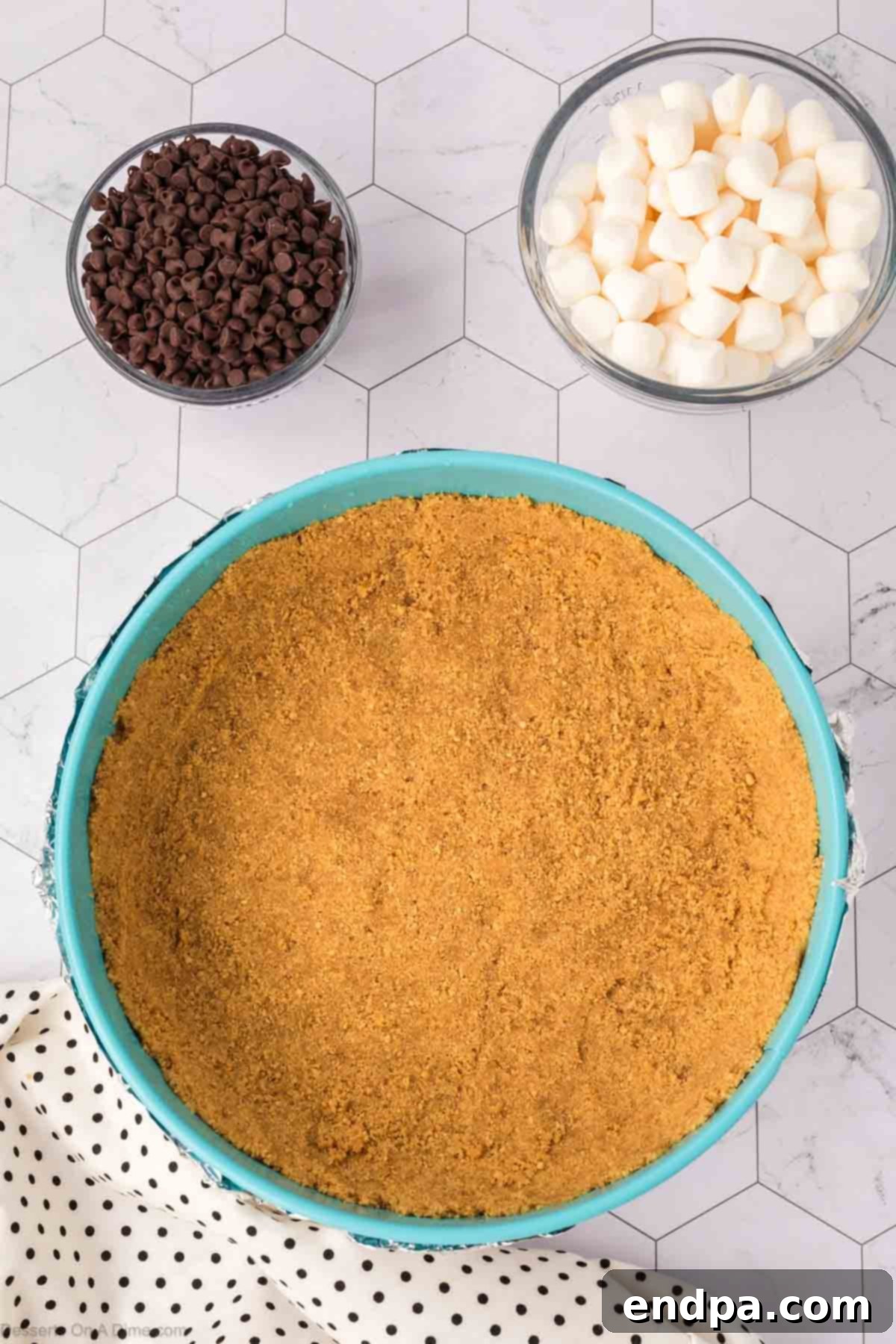 The graham cracker mixture firmly pressed into the bottom and halfway up the sides of a springform pan, creating the solid base for the S'mores Cheesecake.