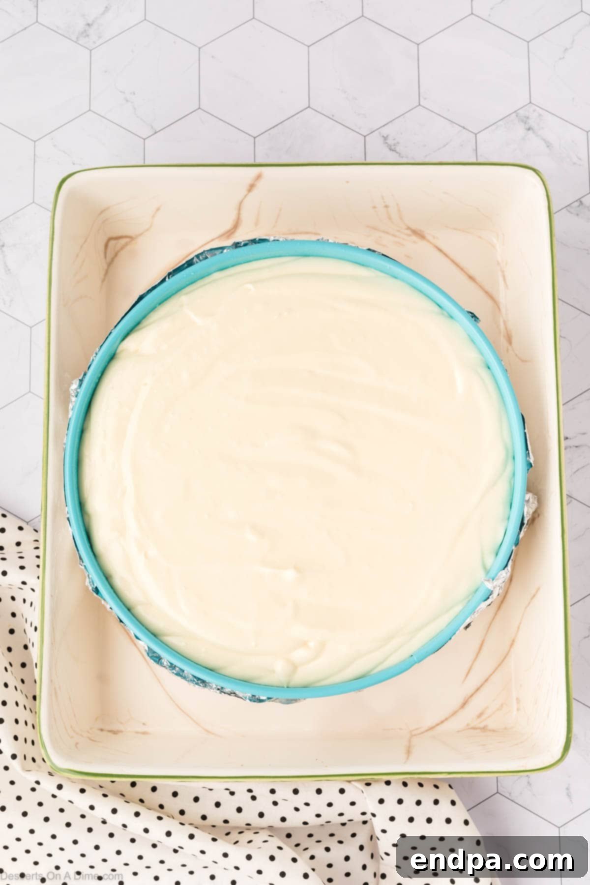 The smooth cheesecake filling being carefully poured into the springform pan over the pre-baked graham cracker and s'mores base, preparing for baking in a water bath.