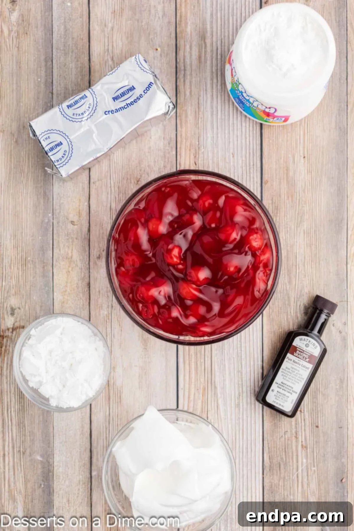 Luscious Cherry Cheesecake Dip 3 Ingredients laid out for Cherry Cheesecake Dip: cream cheese, powdered sugar, vanilla extract, marshmallow creme, whipped topping, and cherry pie filling.