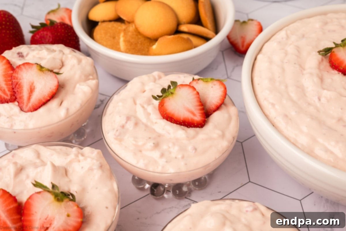 Cheesecake Cloud 2 Cheesecake Fluff served in elegant glass bowls, garnished with fresh strawberries.