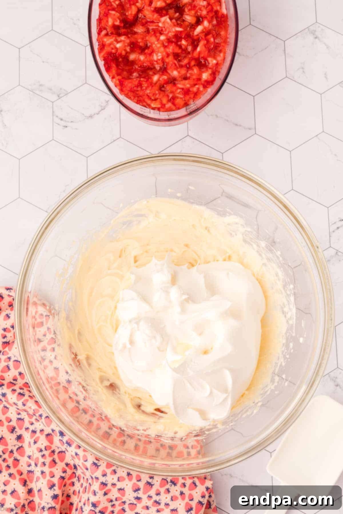 Cheesecake Cloud 5 Whipped topping being gently folded into the cream cheese mixture.