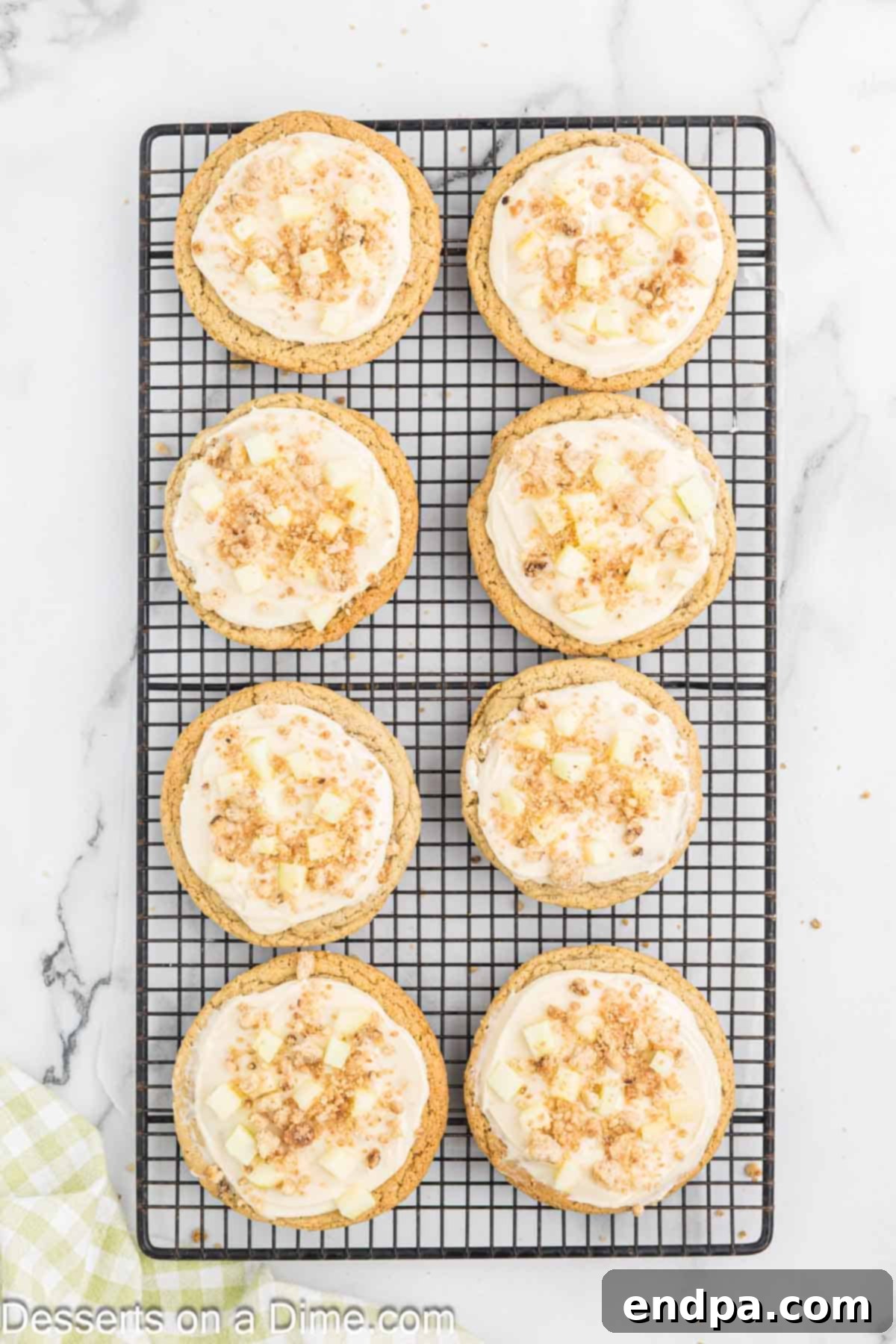 Frosted cookies garnished with diced green apples, streusel topping, and a final caramel drizzle.