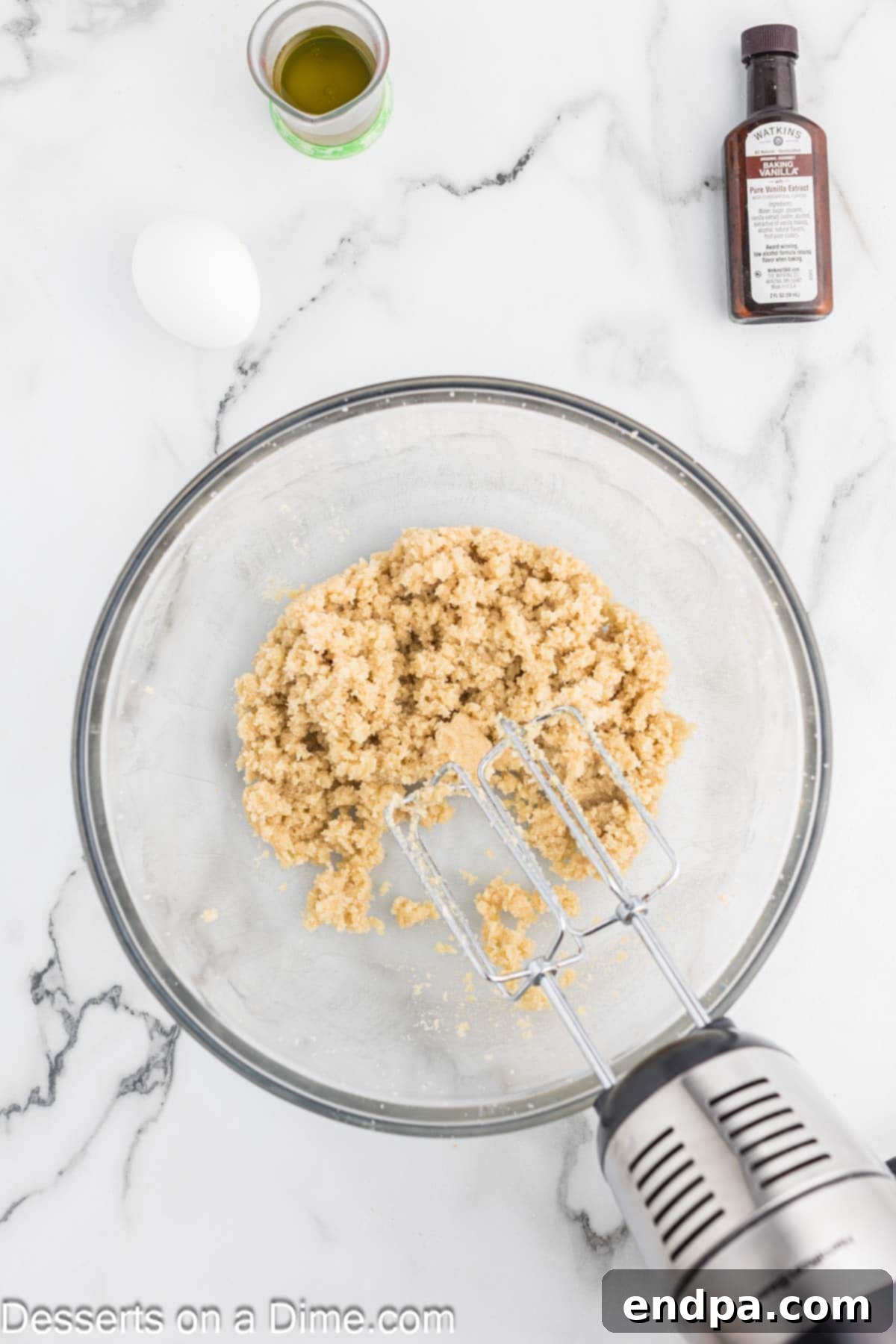 Granulated sugar and brown sugar being added to softened butter in a stand mixer bowl.