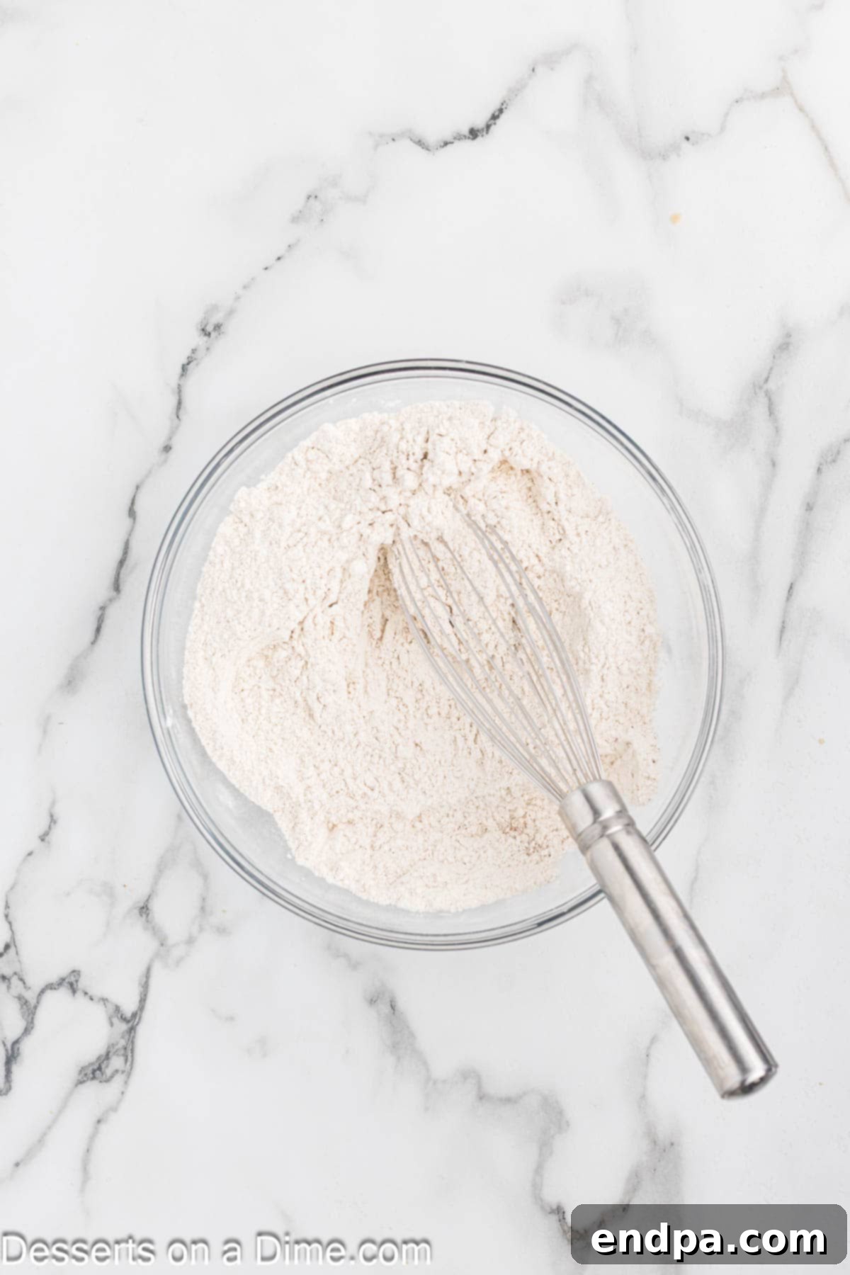 Dry cookie ingredients, including flour, apple pie spice, baking soda, baking powder, and salt, whisked together in a bowl.