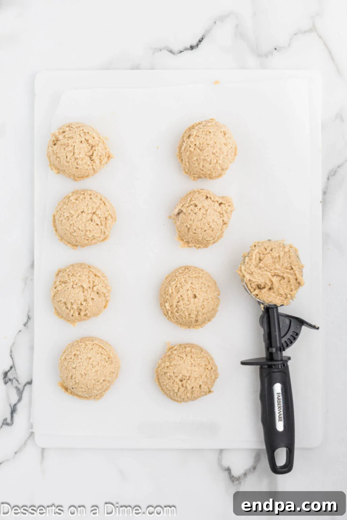 Scooped cookie dough balls placed evenly on a parchment-lined baking sheet.