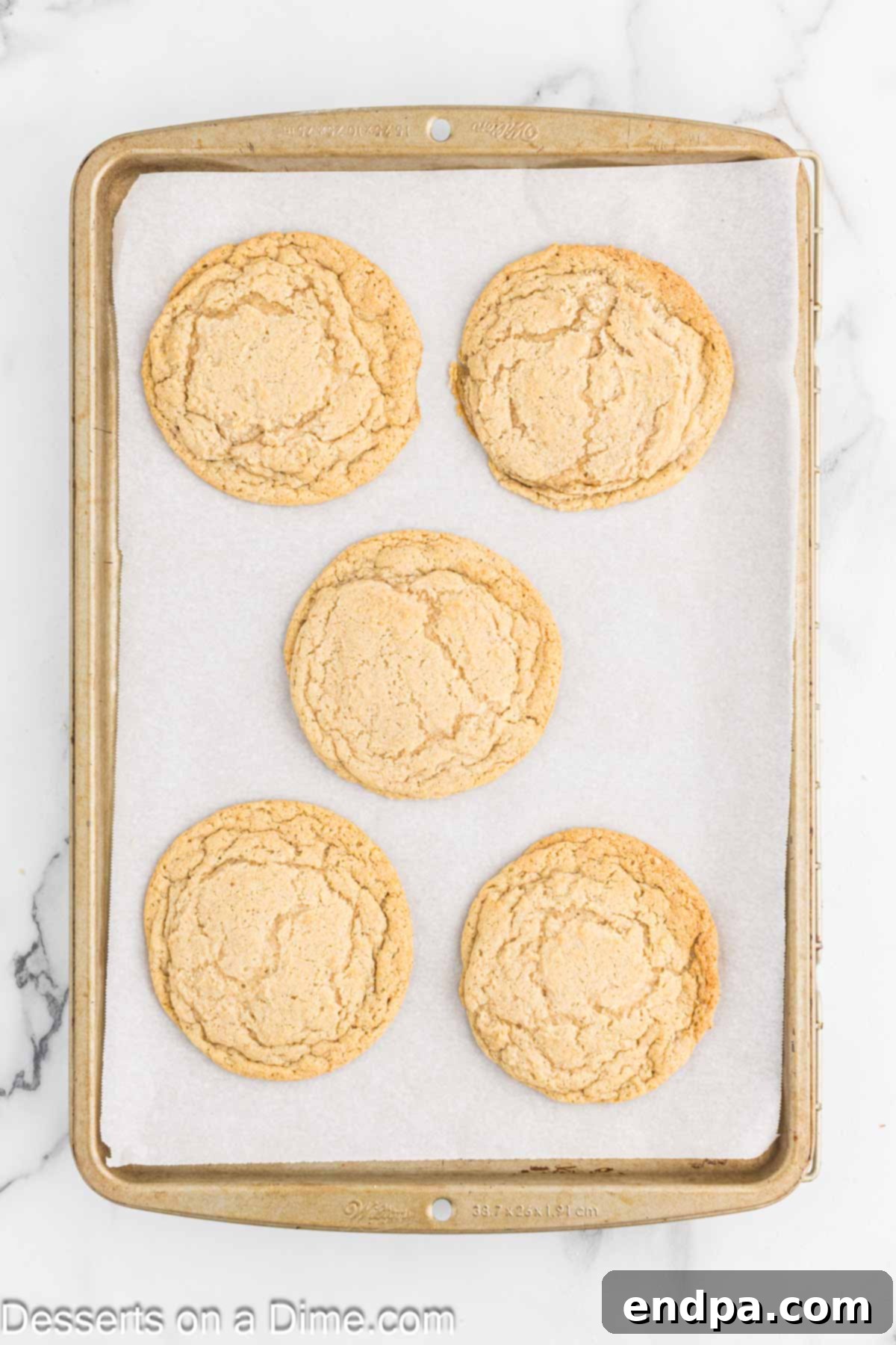 Freshly baked caramel apple cookies cooling on a baking sheet after coming out of the oven.