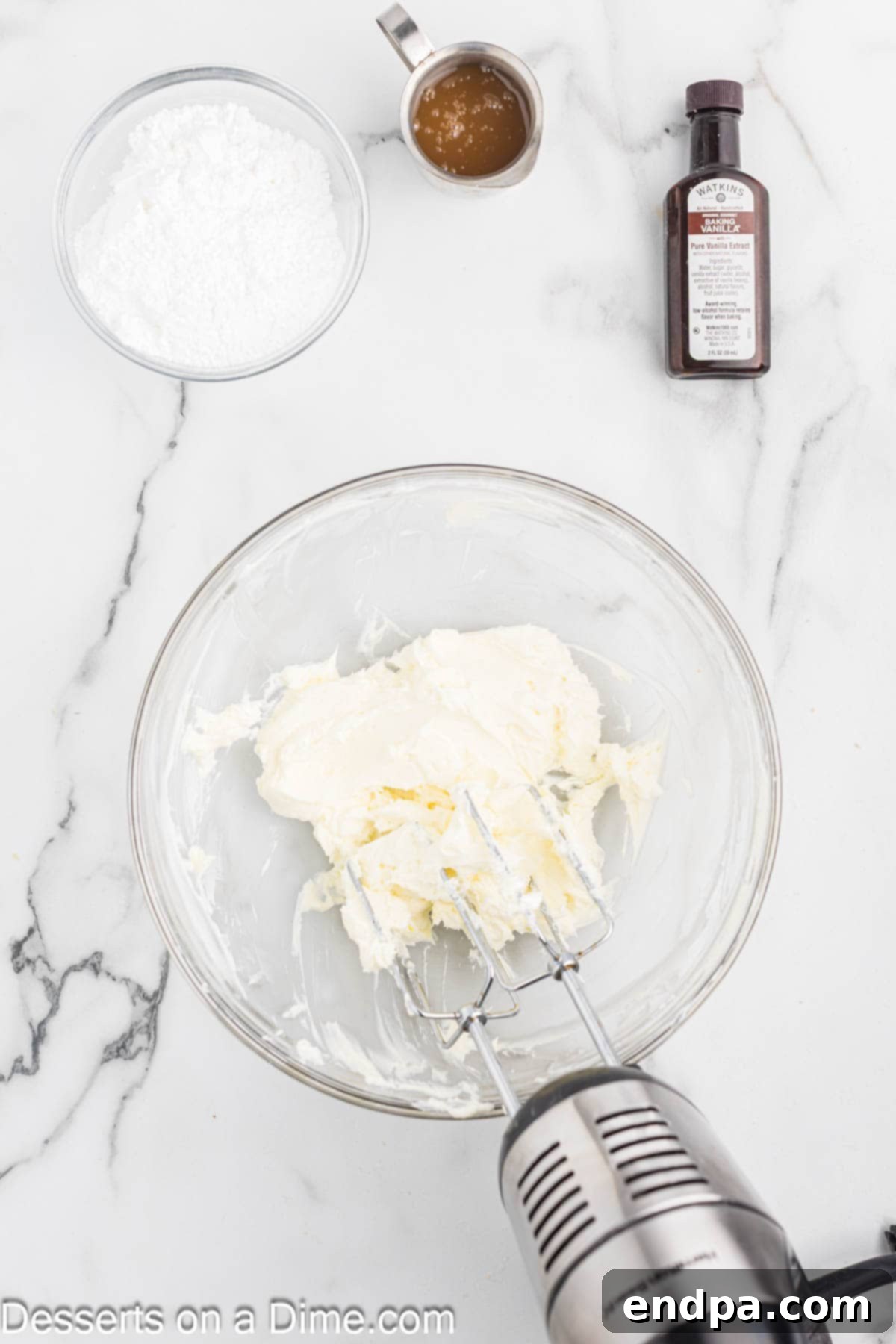 Softened cream cheese being beaten until fluffy and smooth in a mixing bowl.