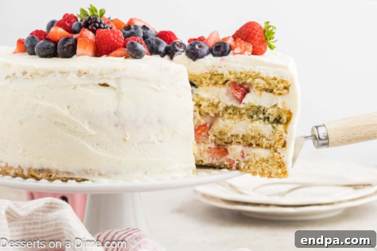 A beautifully sliced Chantilly Cake revealing its layers of vanilla cake, mascarpone cream, and fresh mixed berries.