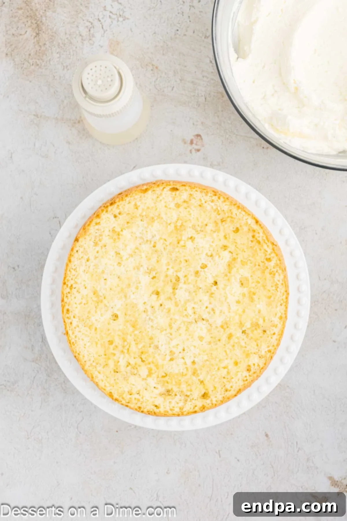 The first cake layer placed on a serving platter and brushed with simple syrup.