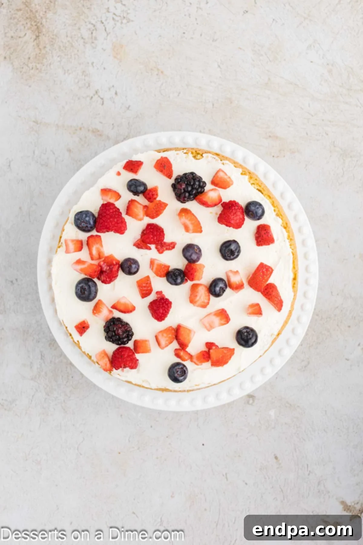 Layers of mascarpone frosting and mixed fresh berries spread over a cake layer.