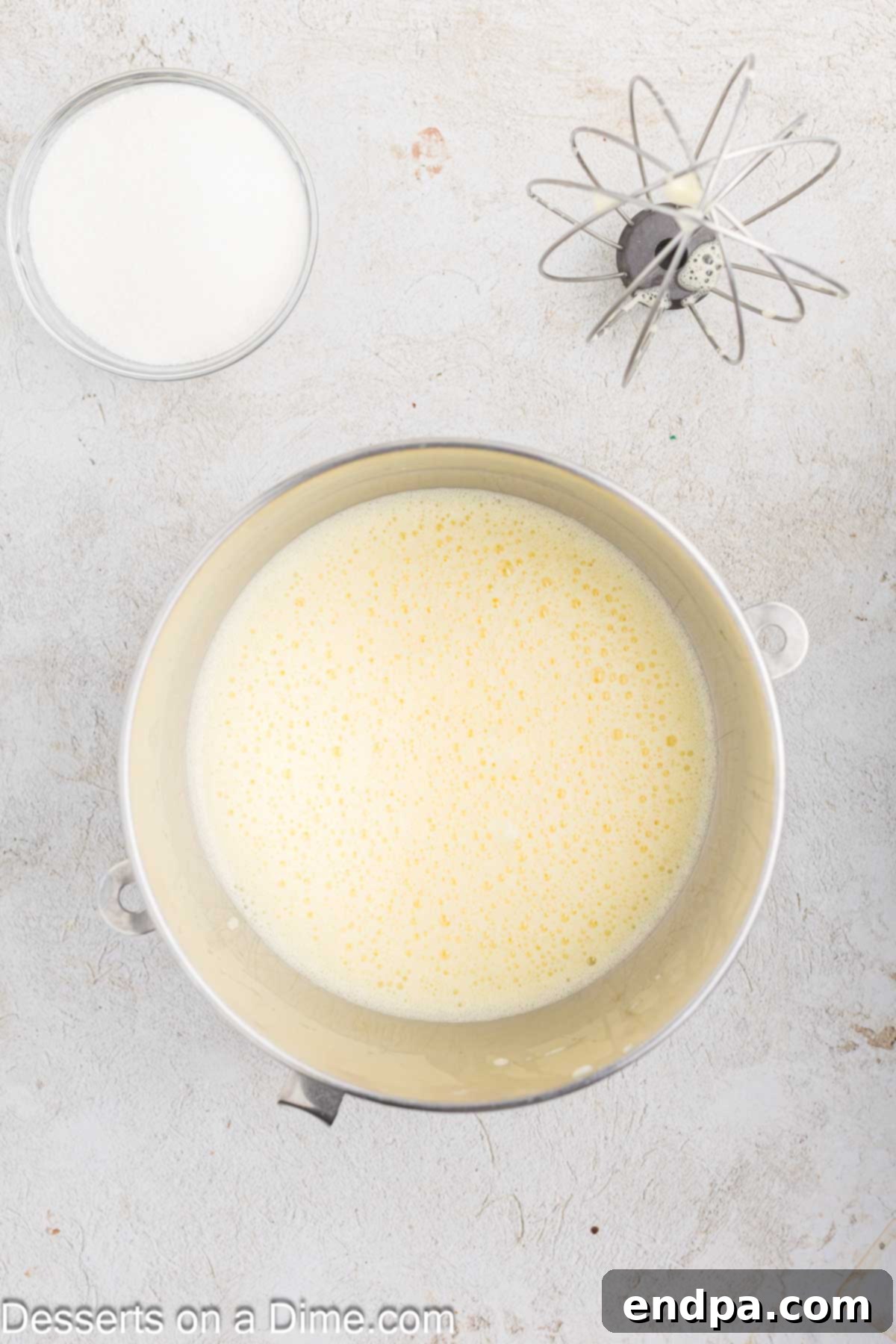 Eggs being beaten until light and foamy in a stand mixer bowl.