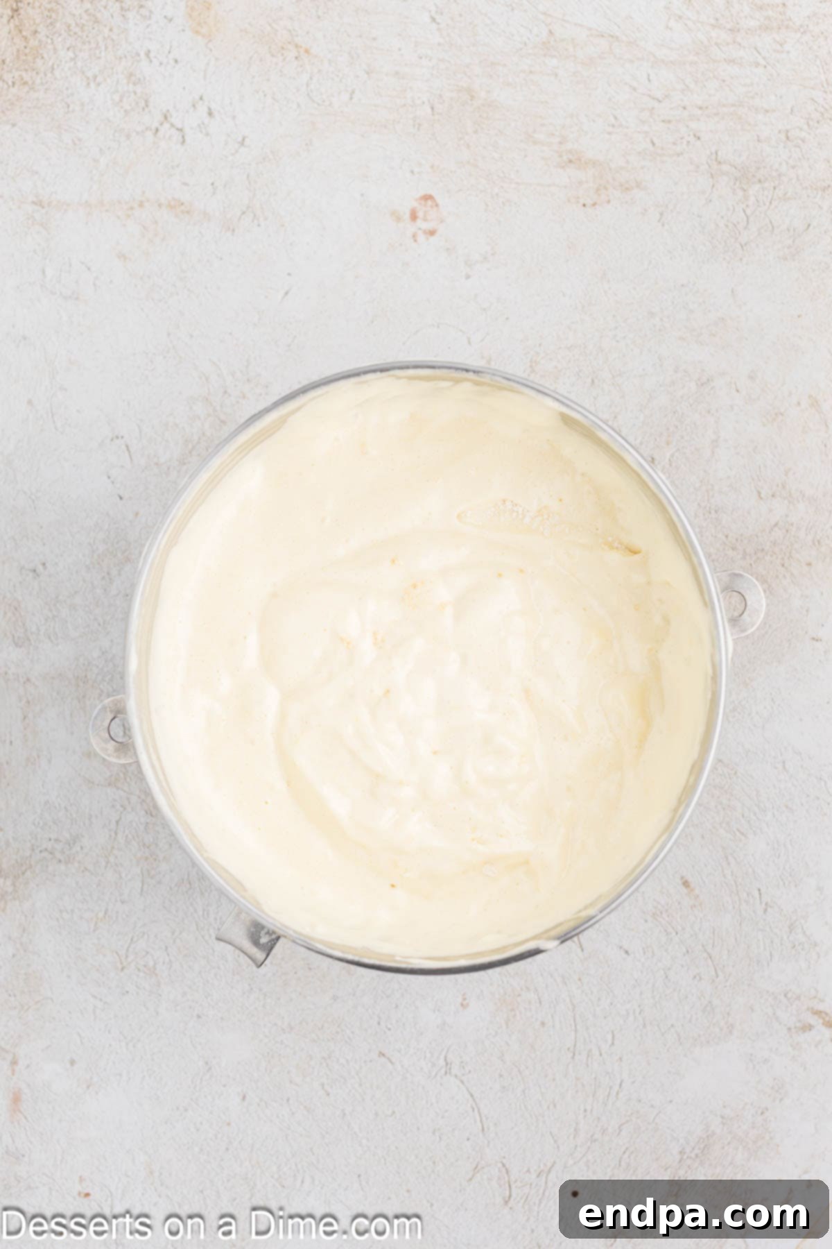 Granulated sugar being gradually added into the foamy egg mixture while the mixer continues to beat.