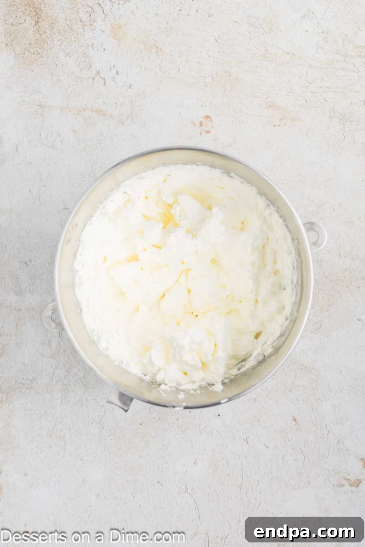 Mascarpone frosting ingredients being mixed until smooth and fluffy in a stand mixer bowl.