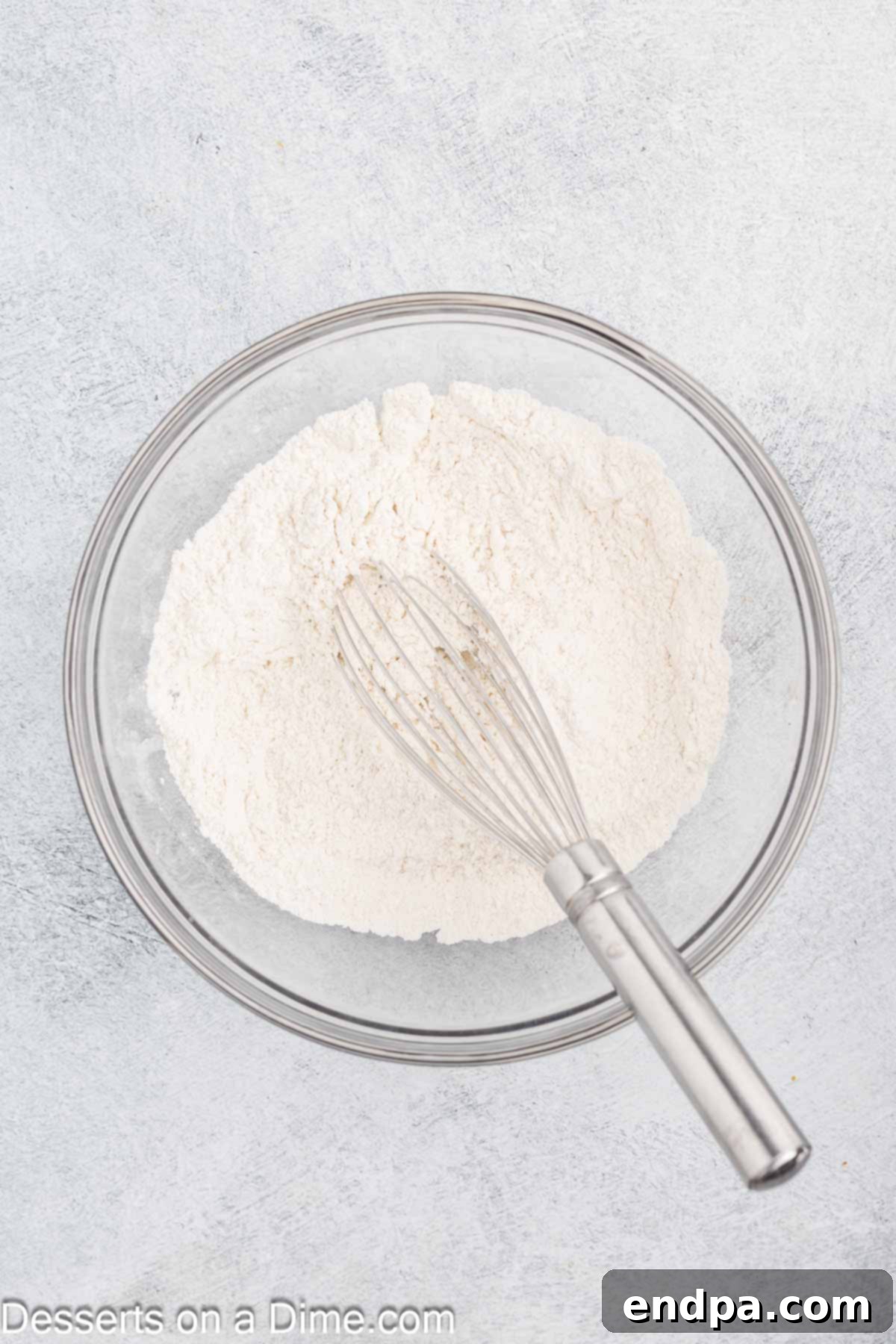 A medium mixing bowl containing combined dry ingredients for peach bread, including flour, cinnamon, baking powder, baking soda, and salt.