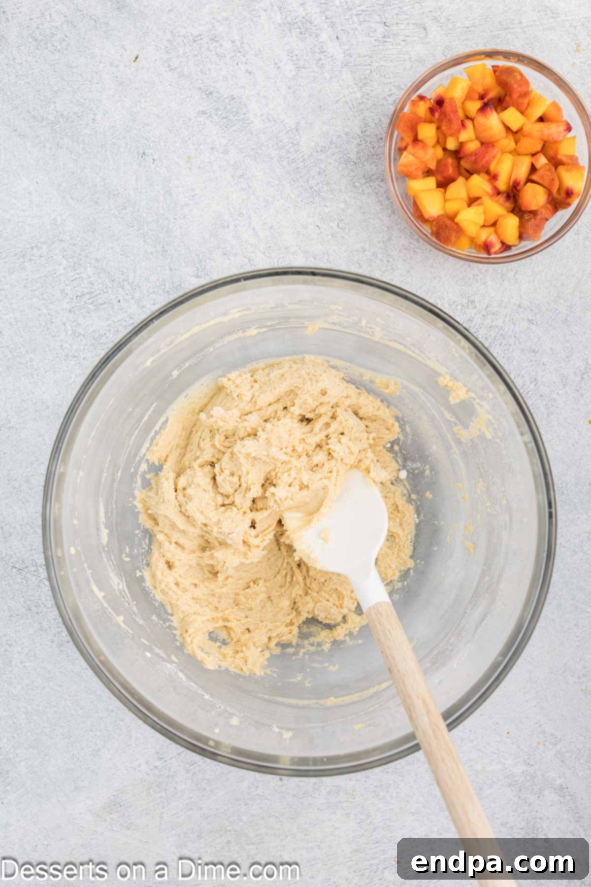 A large mixing bowl containing creamed wet ingredients for peach bread: softened butter, brown sugar, granulated sugar, egg, vanilla extract, and sour cream, appearing light and fluffy.