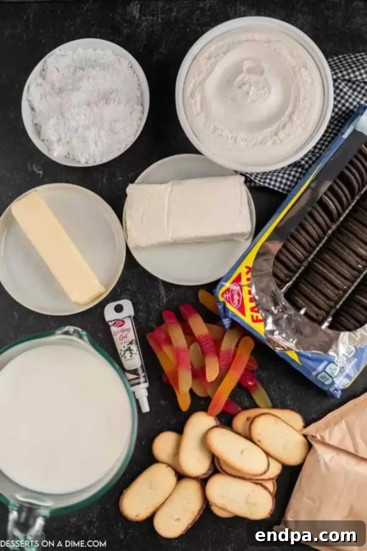 Ingredients for Halloween Dirt Cake including Oreo cookies, cream cheese, butter, powdered sugar, cool whip, chocolate pudding, milk, Milano cookies, gummy worms, candy pumpkins, and black icing.