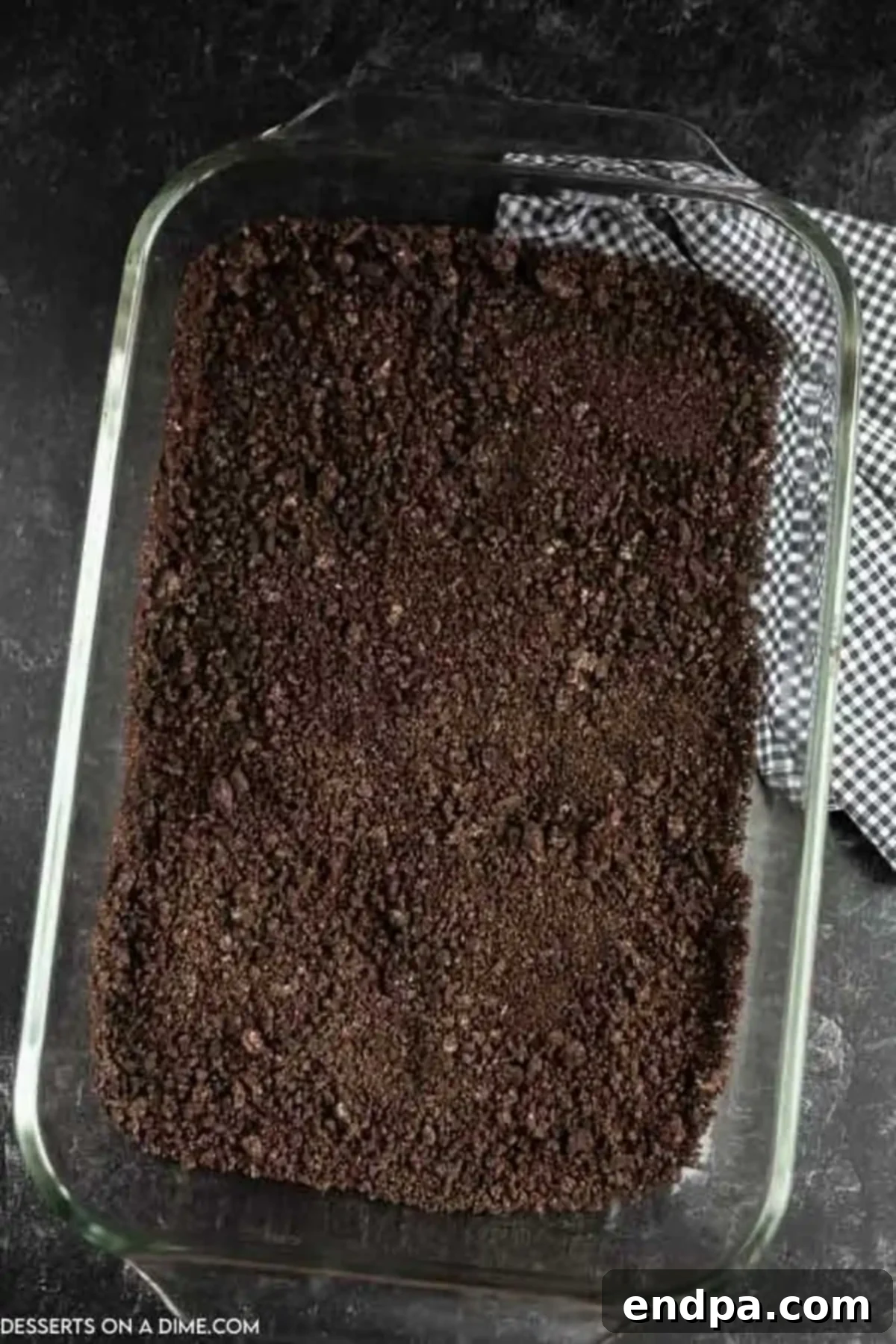 Oreo cookie crumbs evenly spread into the bottom of a 9x13 baking dish.