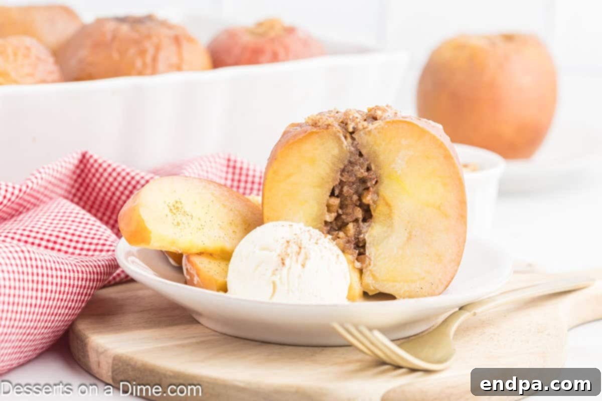 Baked apples with a scoop of vanilla ice cream on a white plate, showcasing a tender, golden-brown exterior and a gooey, spiced filling.