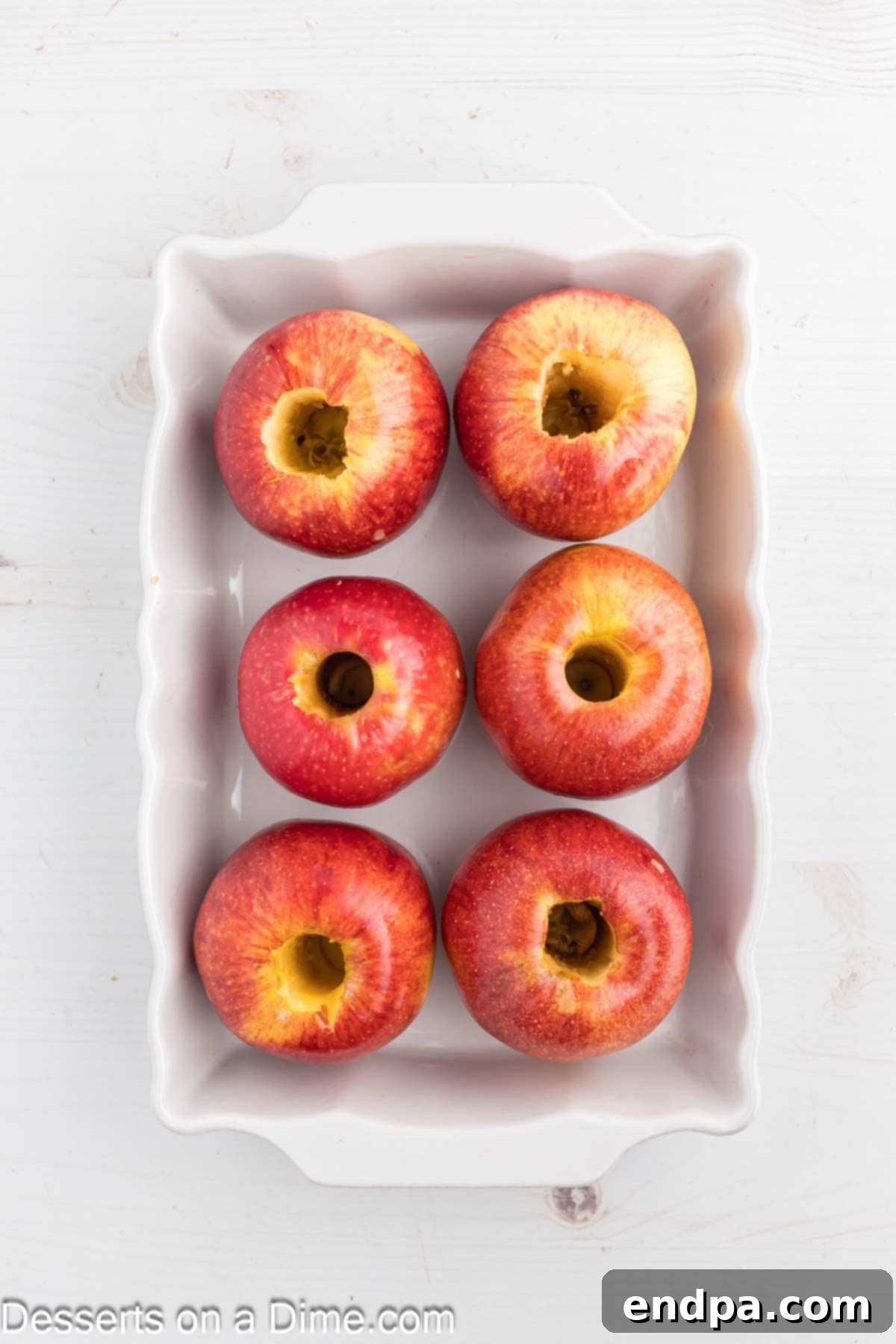 Apples cored and placed in a glass baking dish, ready for filling.