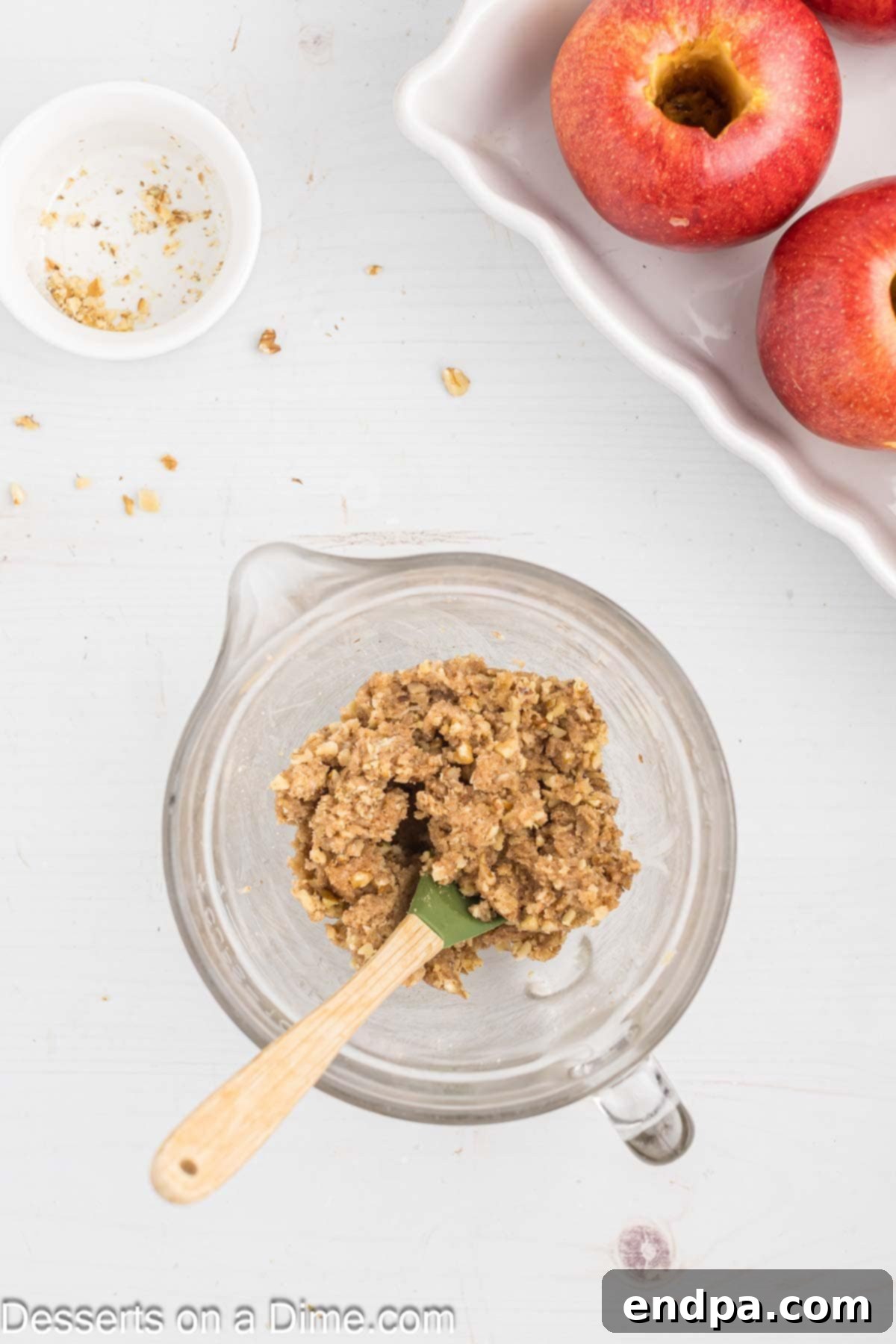 A bowl containing a mixture of brown sugar, cinnamon, butter, and chopped walnuts, blended together to form the apple filling.