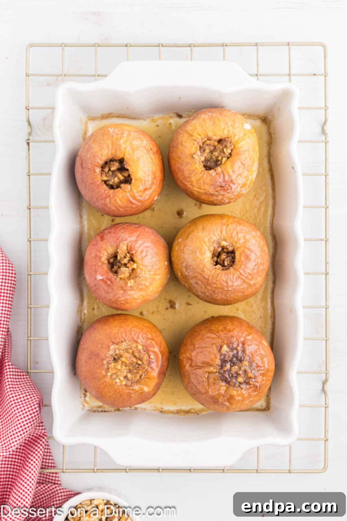 Baked apples, golden and tender, cooling in the baking dish after being removed from the oven.
