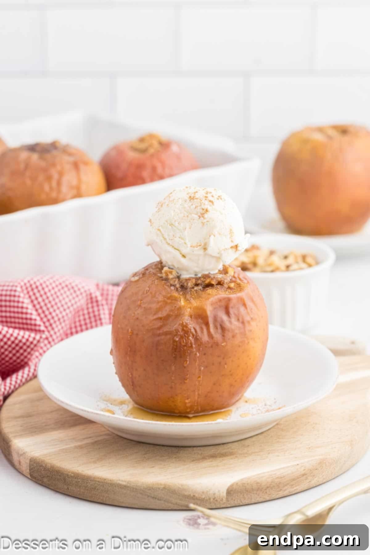 Two baked apples topped with melting vanilla ice cream, served in a white bowl with a spoon, highlighting the warm, inviting nature of the dessert.