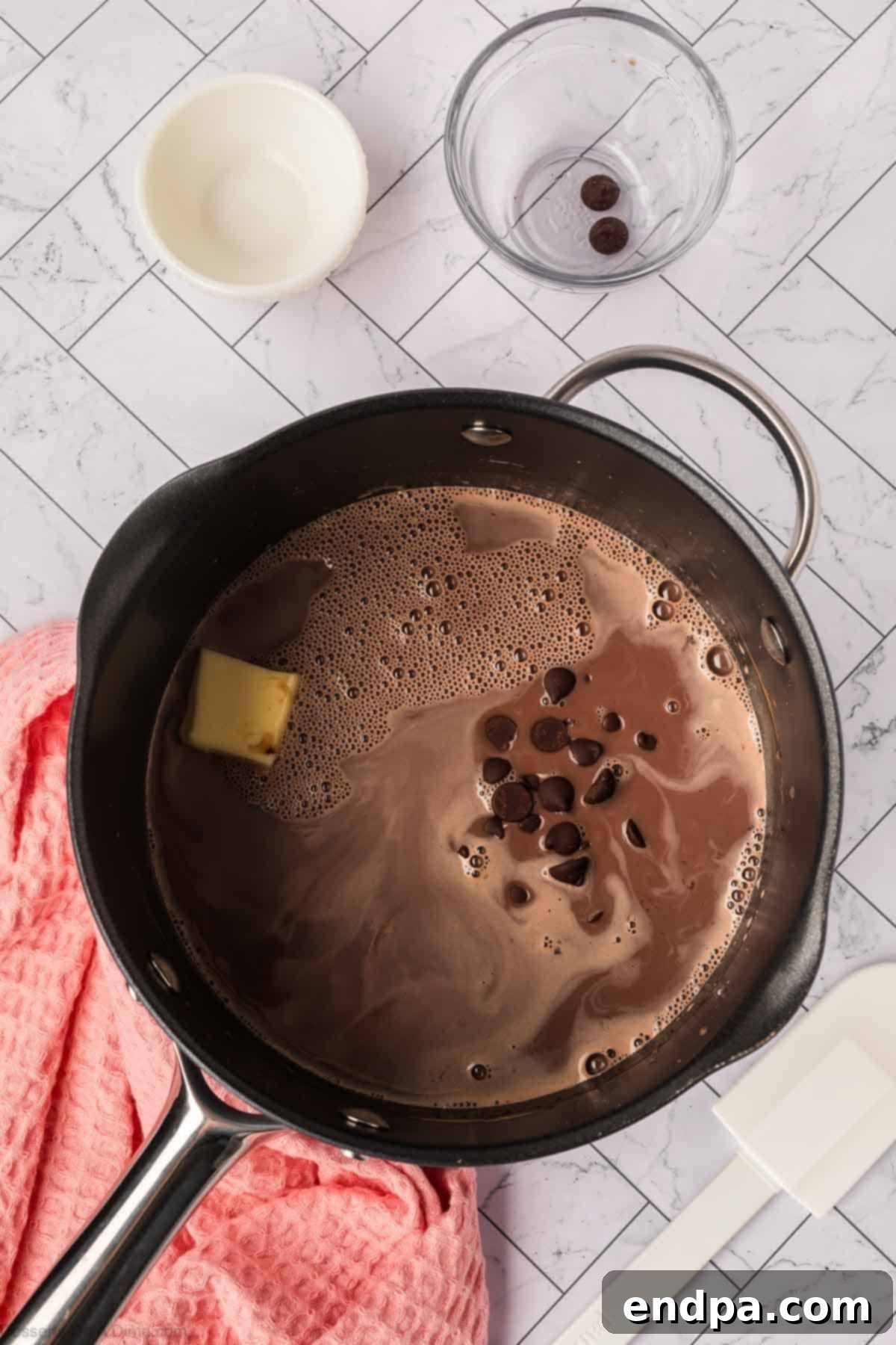 Velvety Dark Chocolate Pudding 5 Half cup of dark chocolate chips and two tablespoons of butter are added to the gently simmering pudding mixture in a saucepan.