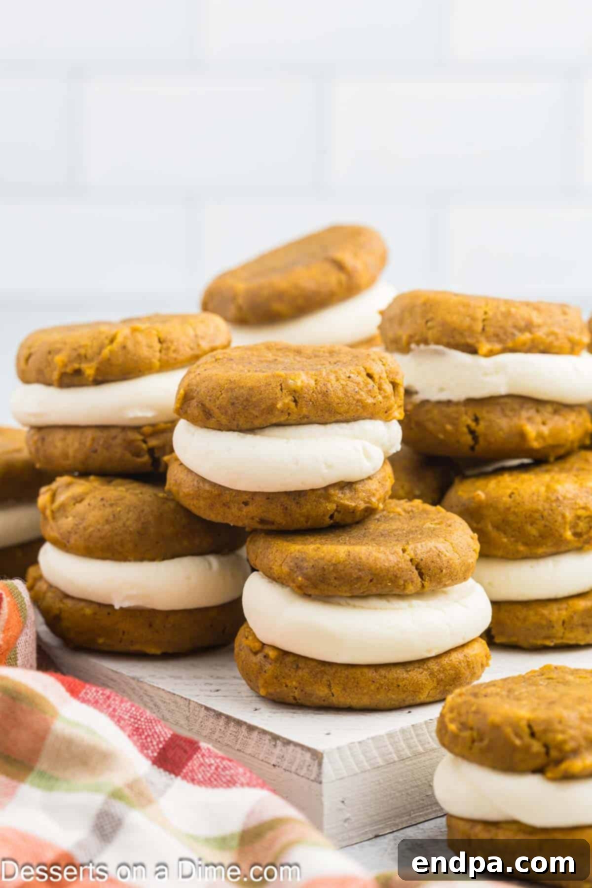 Autumn Pumpkin Cream Pies 12 A delightful platter of perfectly assembled Pumpkin Whoopie Pies, stacked invitingly, garnished with a sprinkle of cinnamon, ready to be enjoyed as a festive fall dessert.