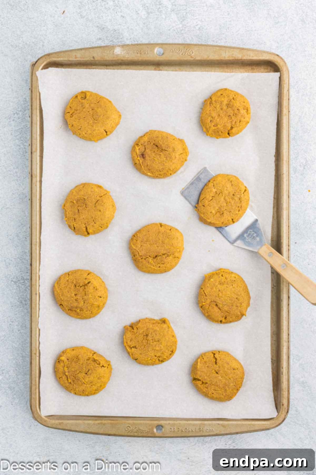 Autumn Pumpkin Cream Pies 8 Freshly baked pumpkin cookies are carefully cooling on a wire rack after being transferred from the baking sheet, highlighting the essential cooling process before filling.