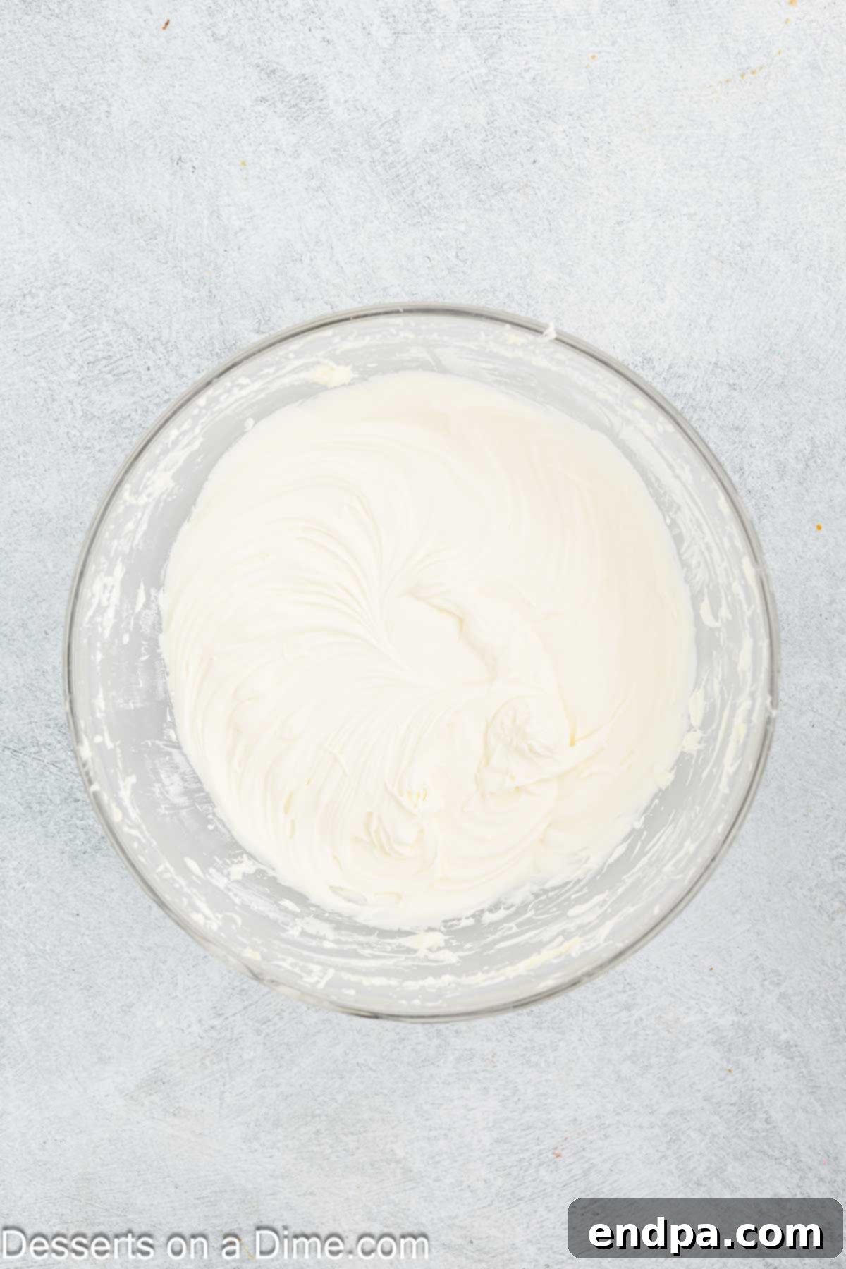 Autumn Pumpkin Cream Pies 10 Powdered sugar being gradually incorporated into the smooth cream cheese and butter mixture in a mixing bowl, illustrating the process of achieving a perfectly sweetened and thick frosting.