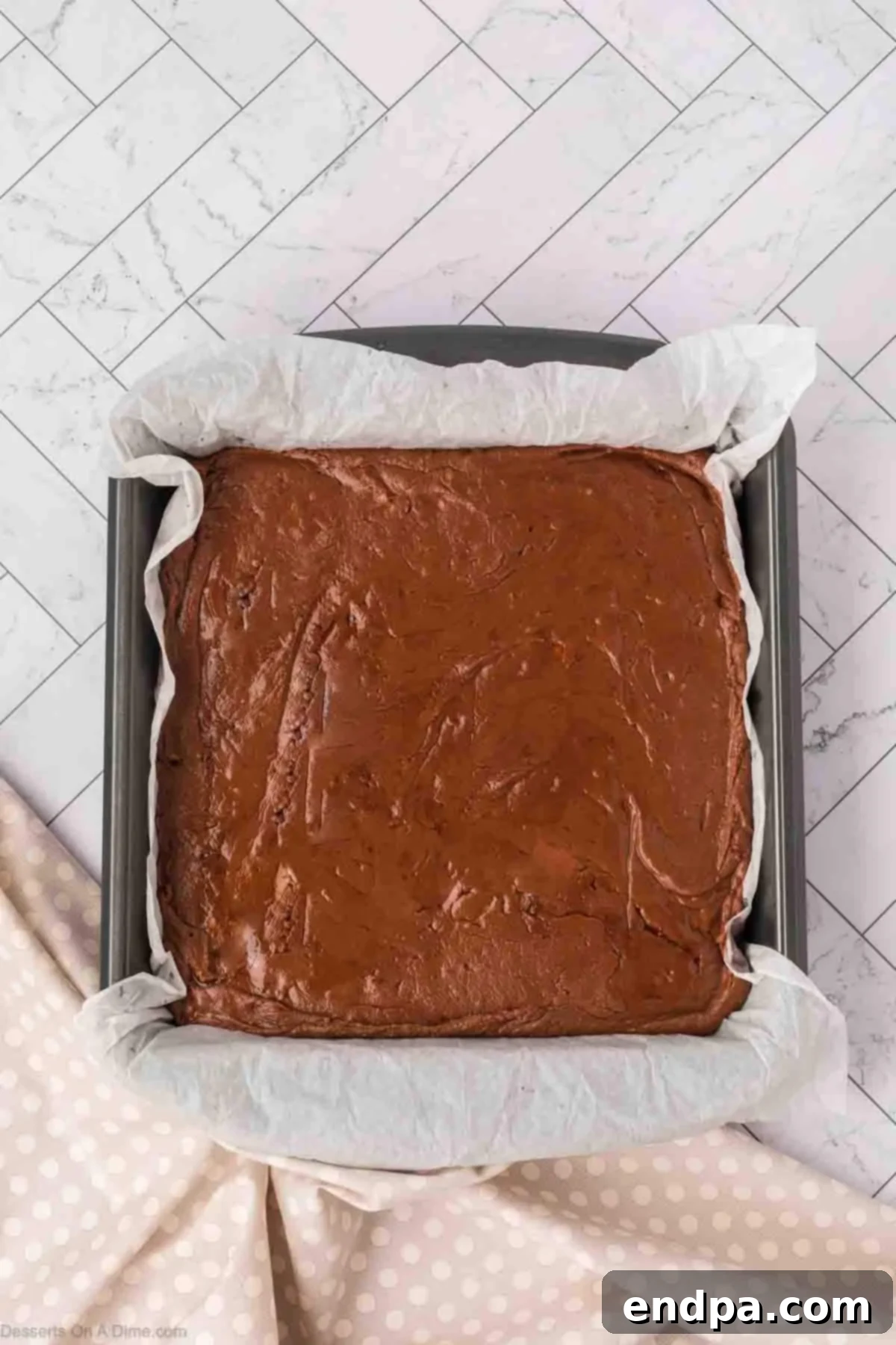 The set fudge block being lifted from the pan using the parchment paper overhang.