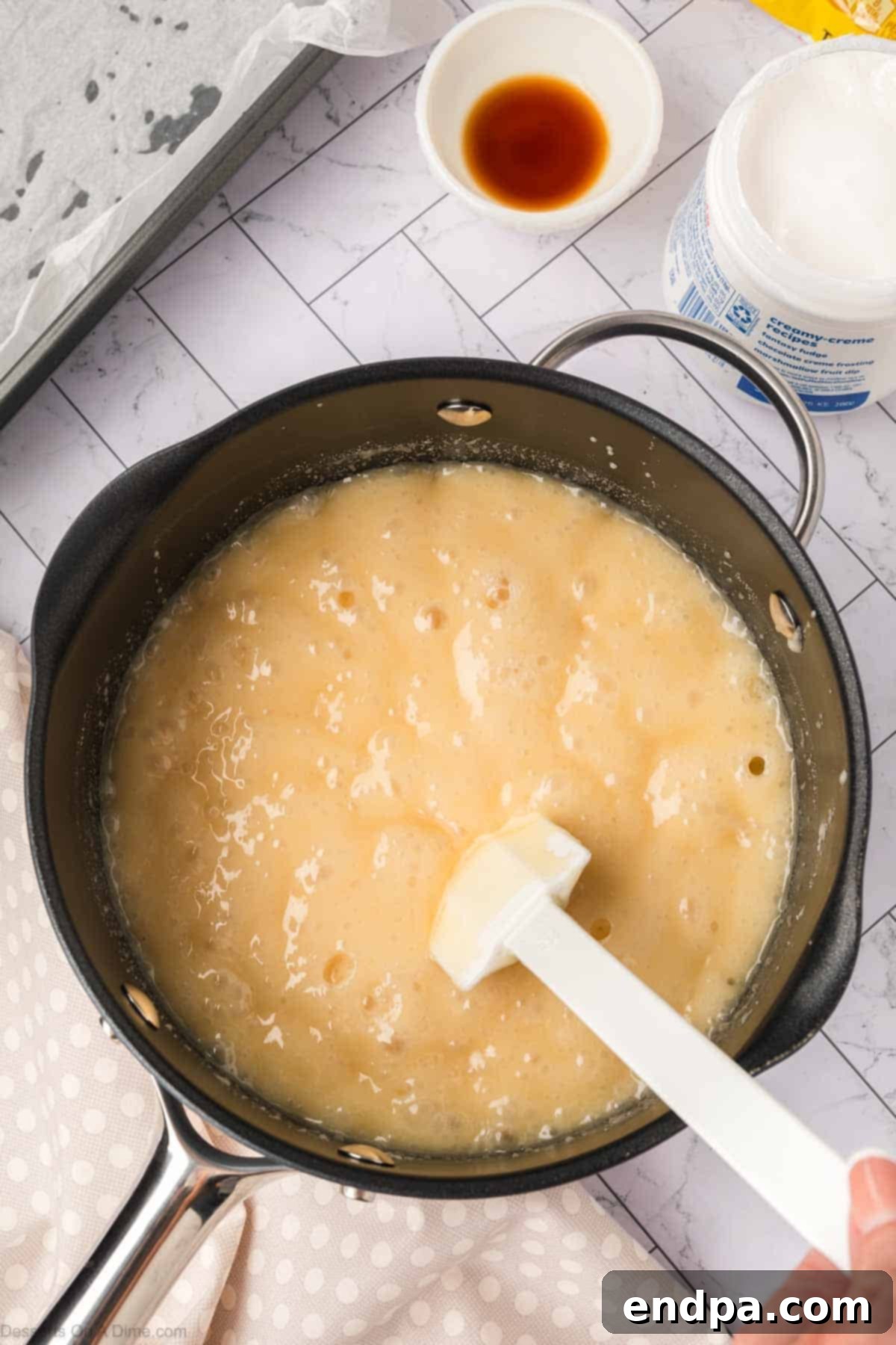 Fudge mixture boiling vigorously in the saucepan, showing a frothy surface.