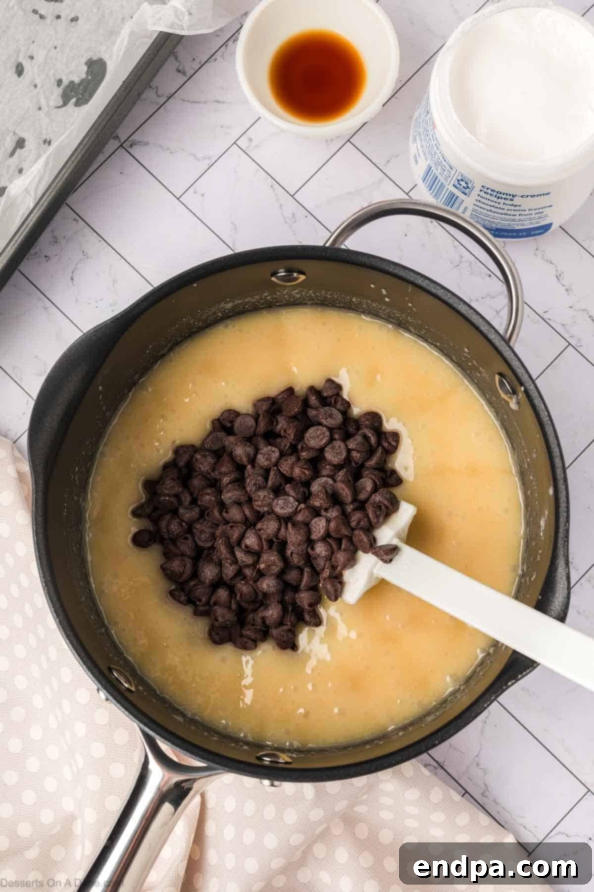 Semisweet chocolate chips just added to the hot fudge mixture in the saucepan, beginning to melt.