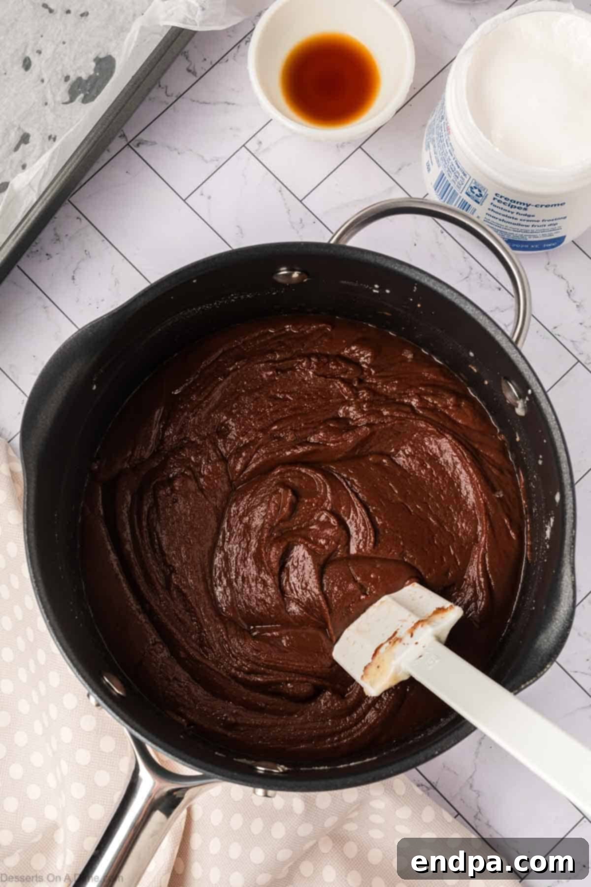 Marshmallow fluff, vanilla extract, and chopped pecans being added to the melted chocolate mixture.