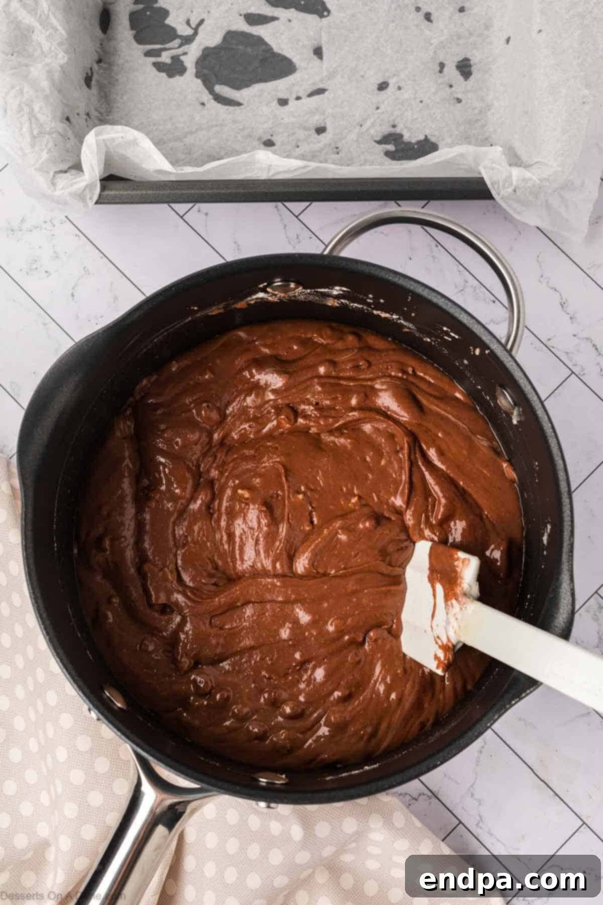 Fudge mixture spread evenly into the parchment-lined baking pan, ready for refrigeration.