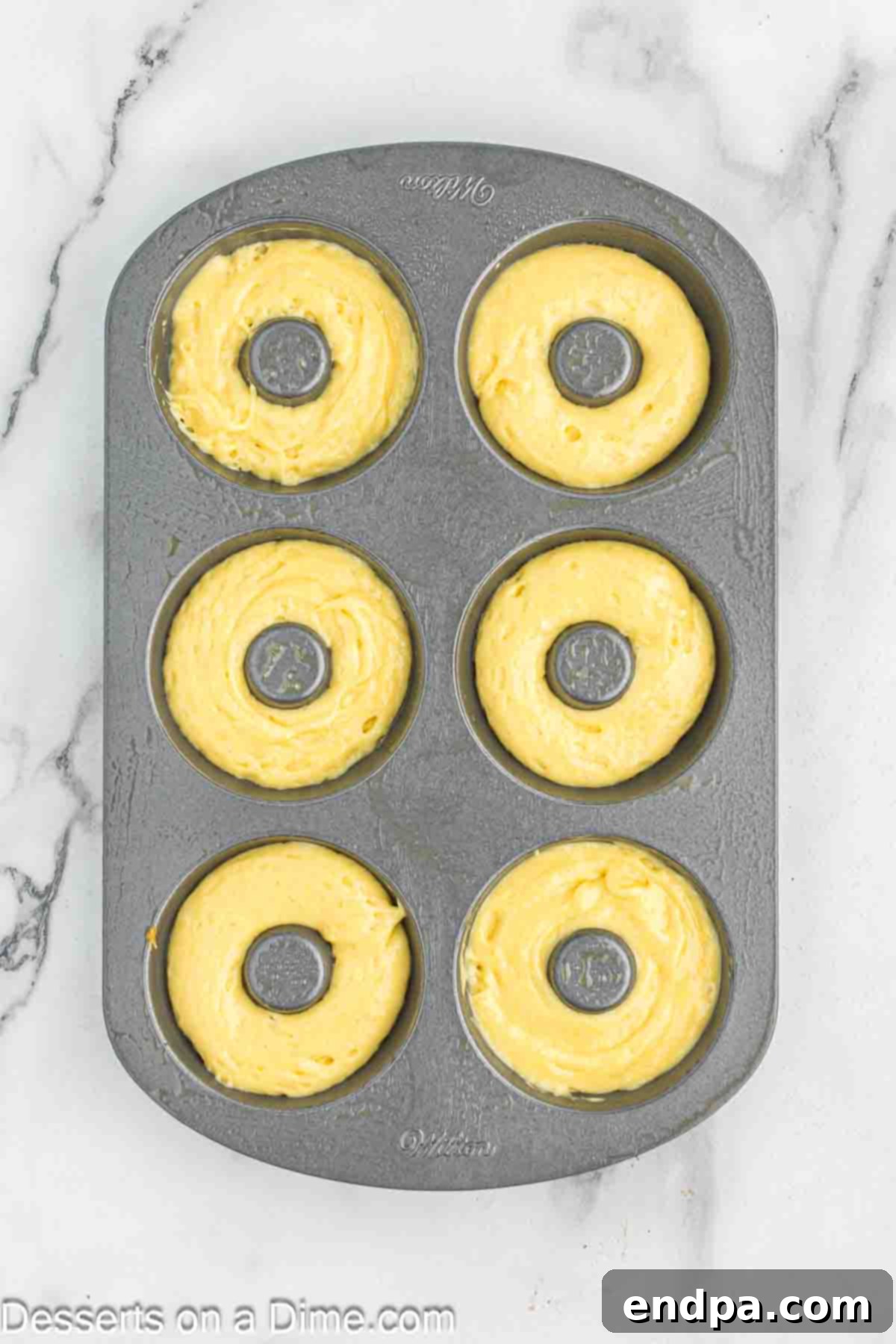 Batter piped into donut pan.