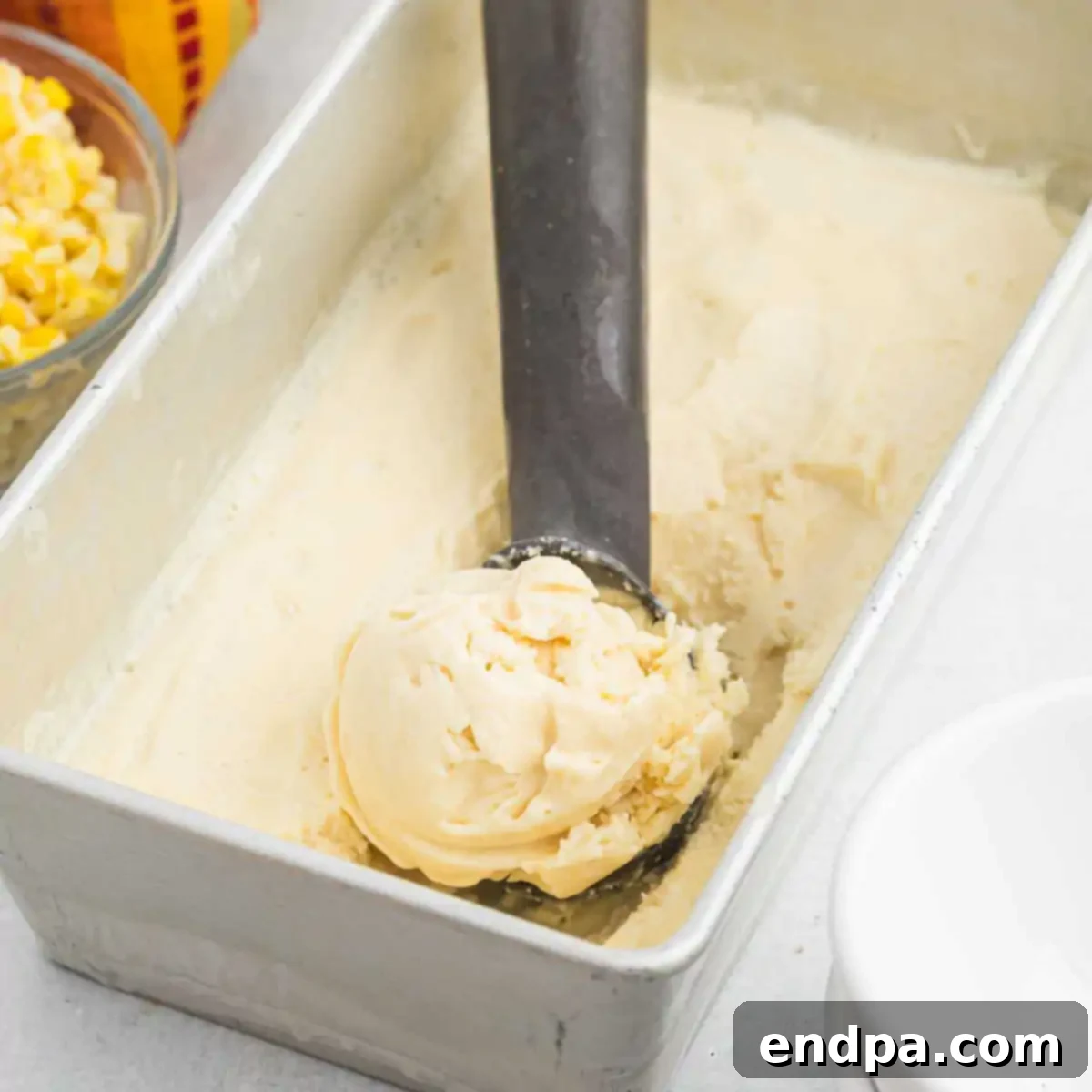 Close-up of a scoop of creamy corn ice cream in a bowl.