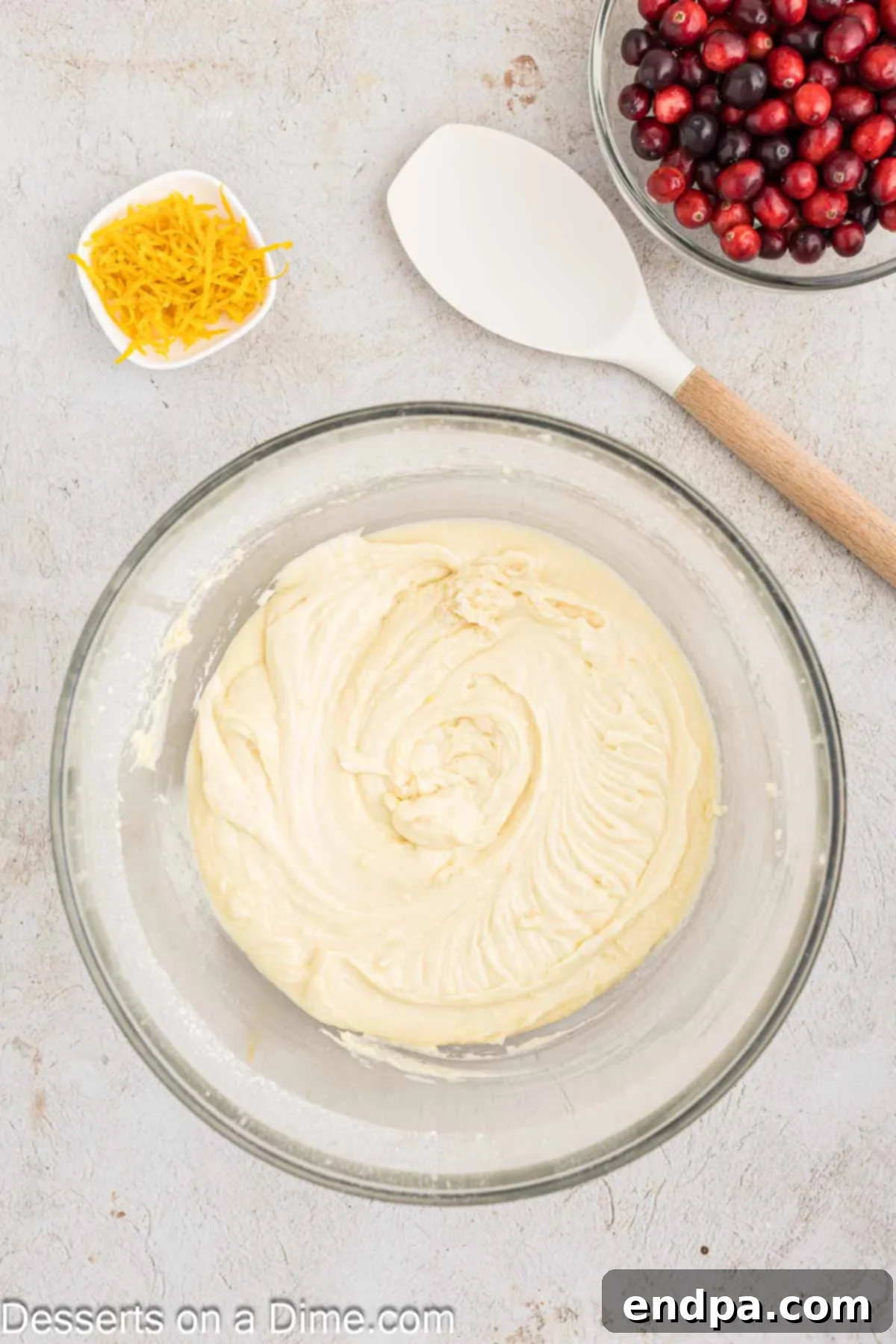 Orange cranberry bread batter combined in a mixing bowl, showing a smooth and slightly thick consistency.