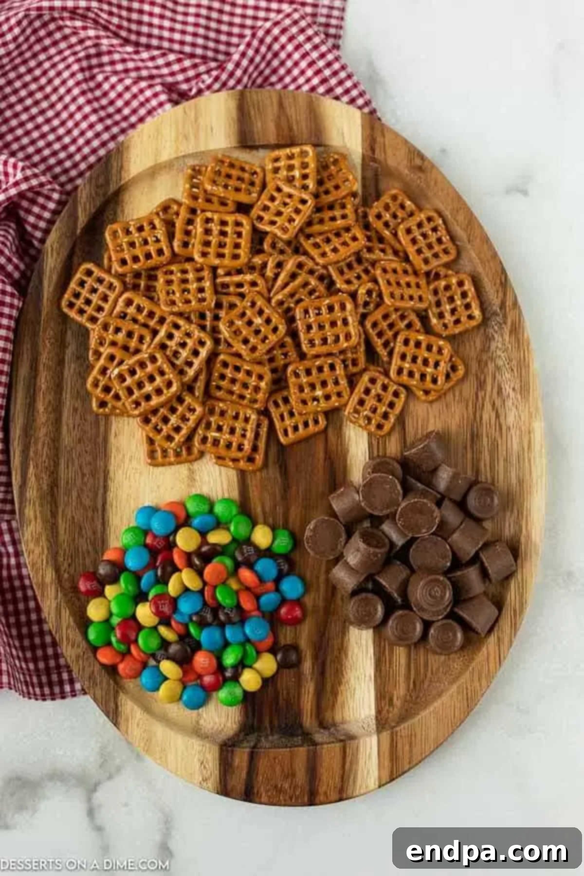 Key ingredients laid out for Rolo Pretzel Bites: snap pretzels, Rolo candies, and M&Ms chocolate candies.