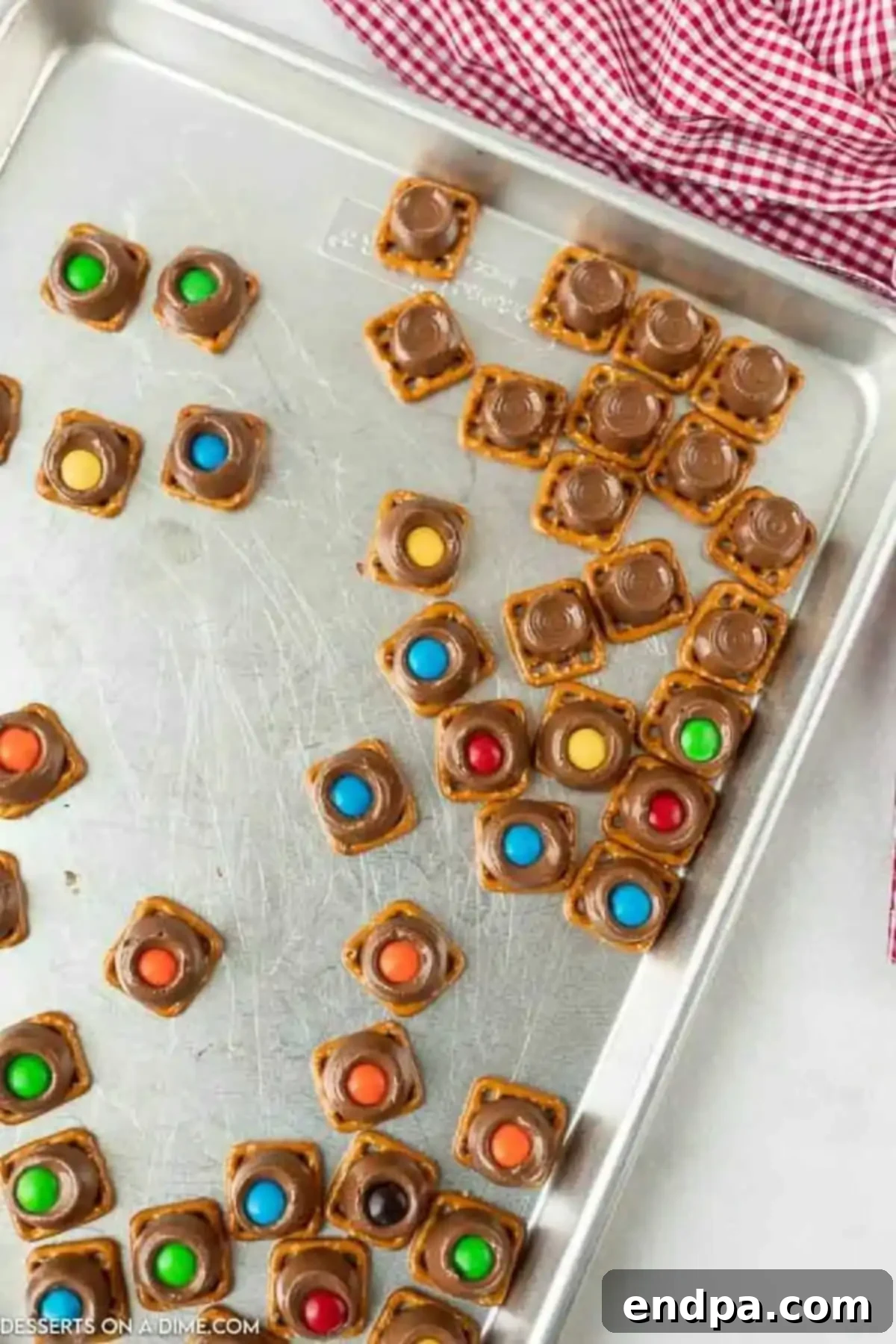 M&Ms being pressed onto the softened Rolo candies on top of pretzels.